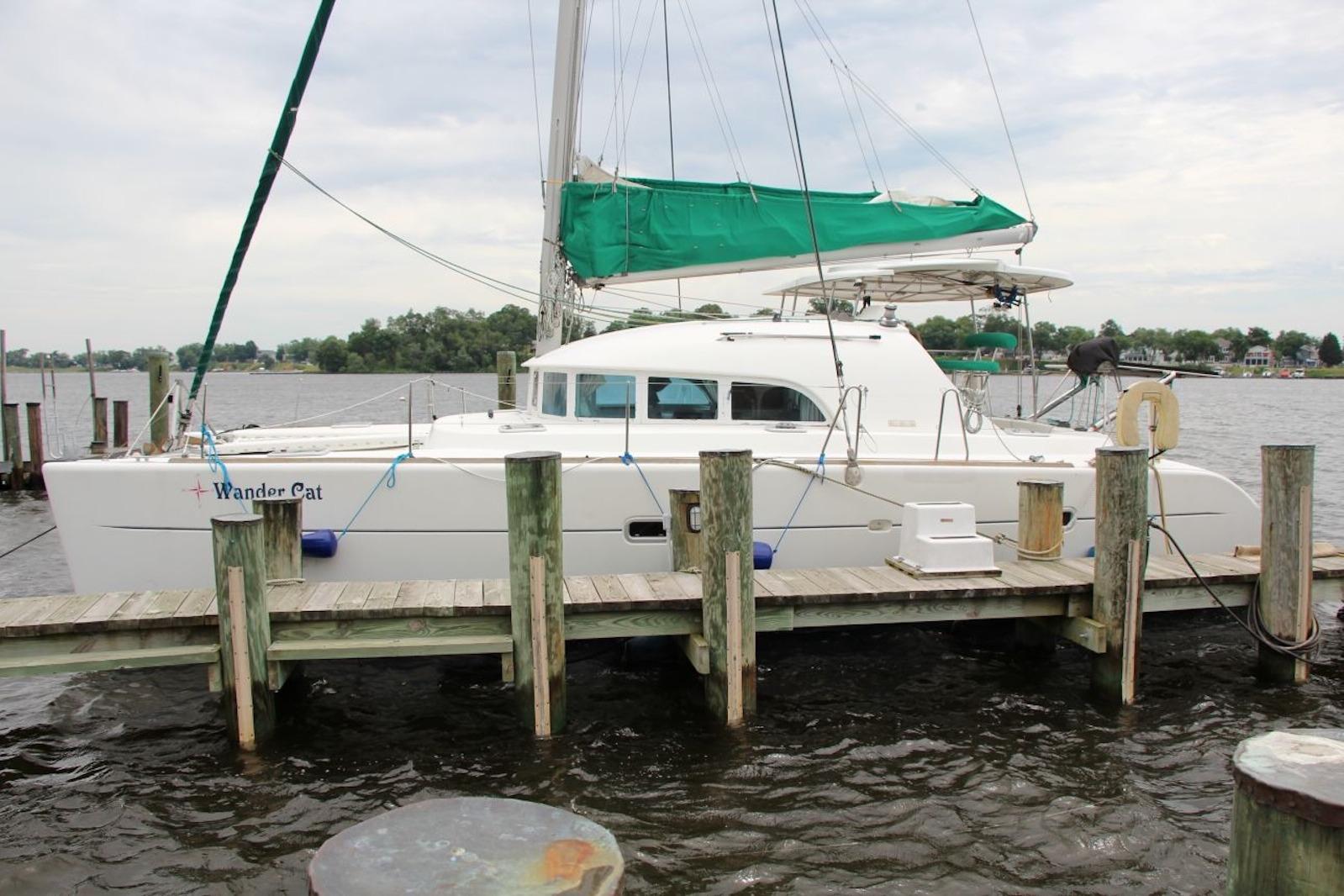 2004 Lagoon 380 catamaran docked at a marina with green sail cover.
