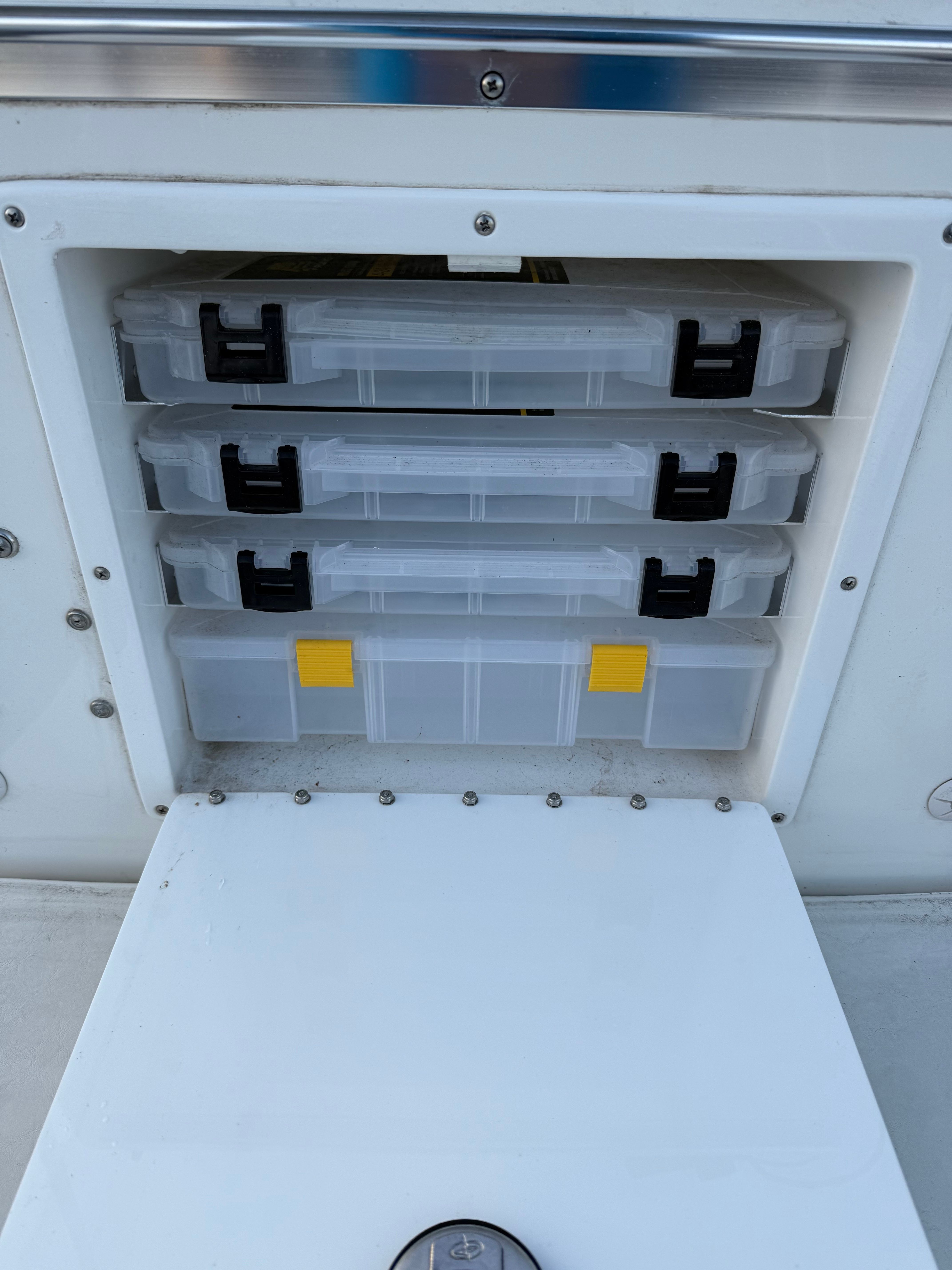 Storage compartment with three clear tackle boxes on a 2004 Custom Sea Fly boat.
