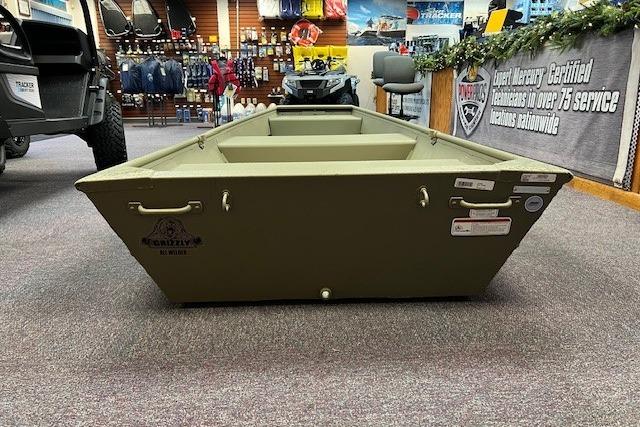 2026 Tracker Grizzly 12 Jon boat displayed in a showroom with outdoor gear.