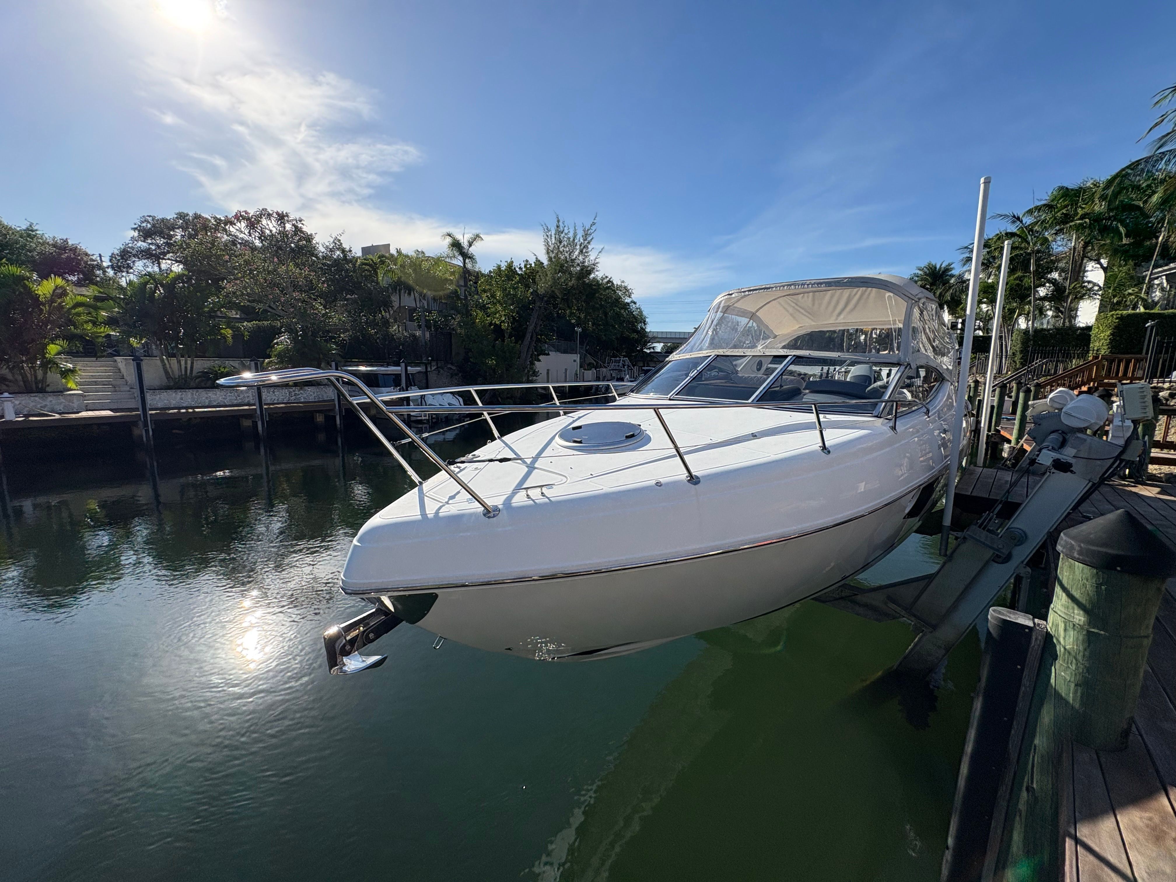 A 2023 Schaefer 303 Sport boat is suspended above the water in a calm canal.