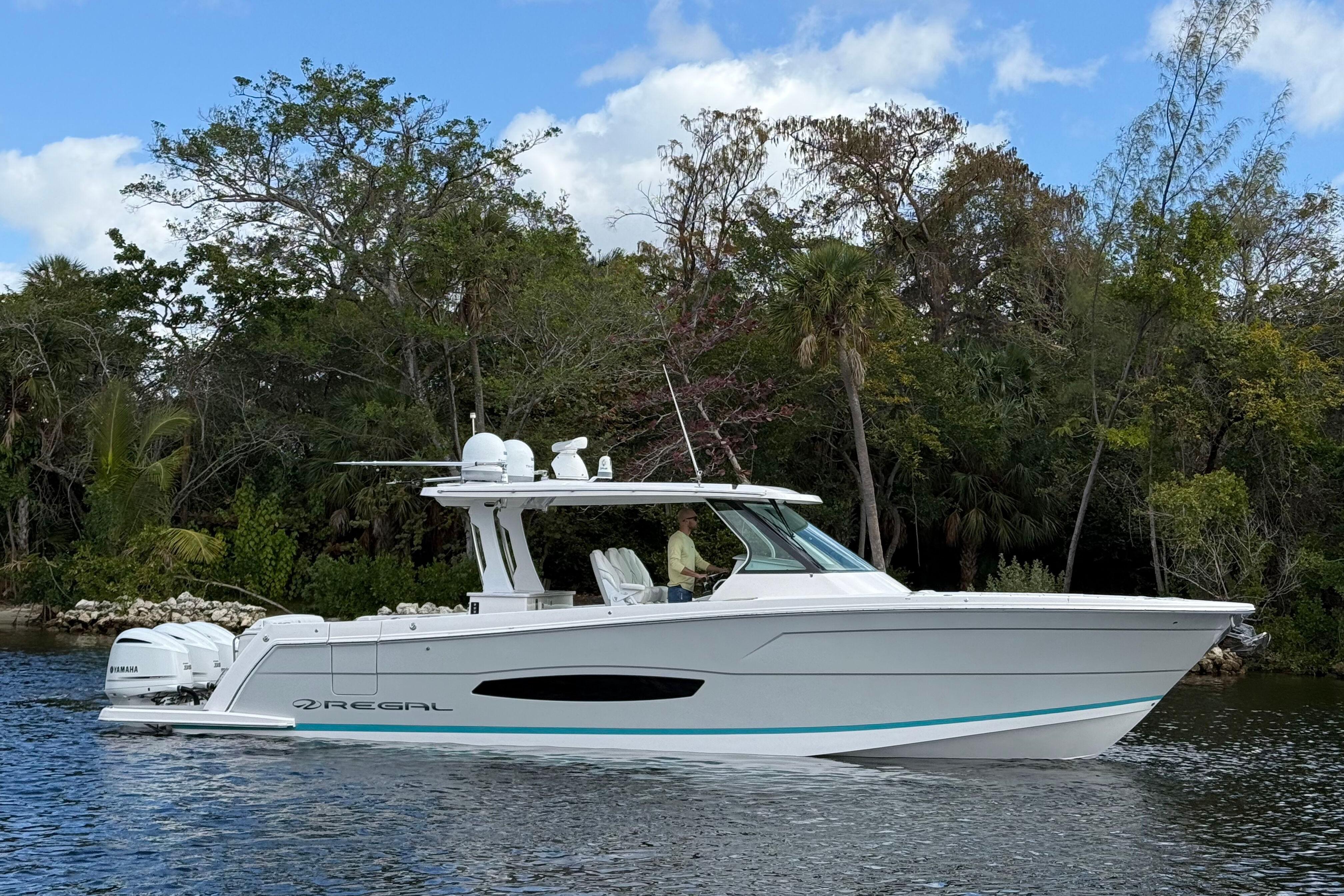 2020 Regal 38 SAV boat cruising on a scenic waterway with lush greenery.