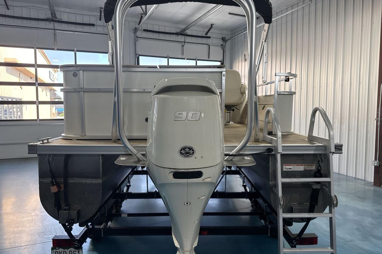 2018 Landau Alure 212 Fish pontoon boat with 90 HP engine in a garage.