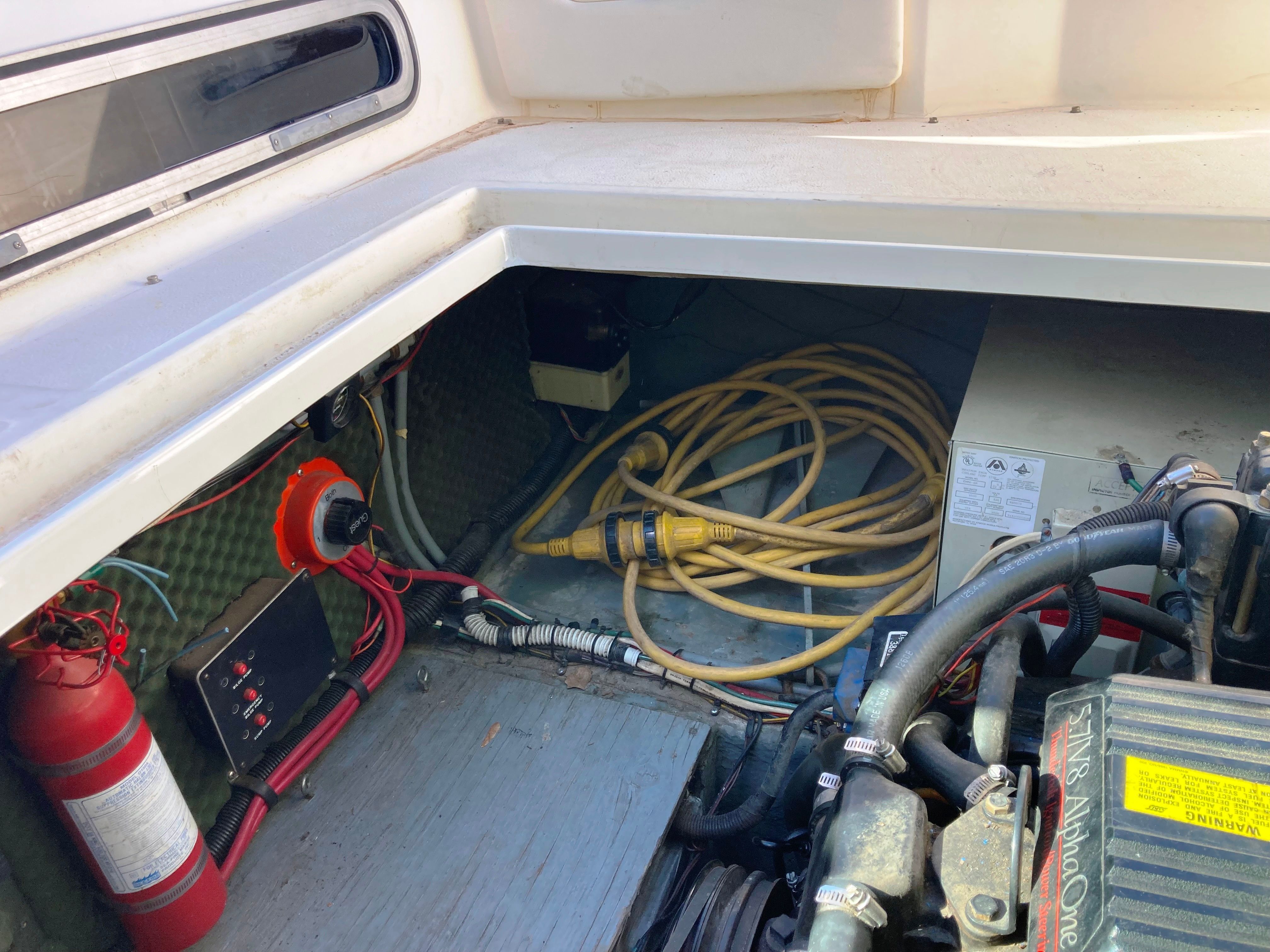 A view of a 1991 Sea Ray 220 Sundancer's engine compartment with cables and a fire extinguisher.