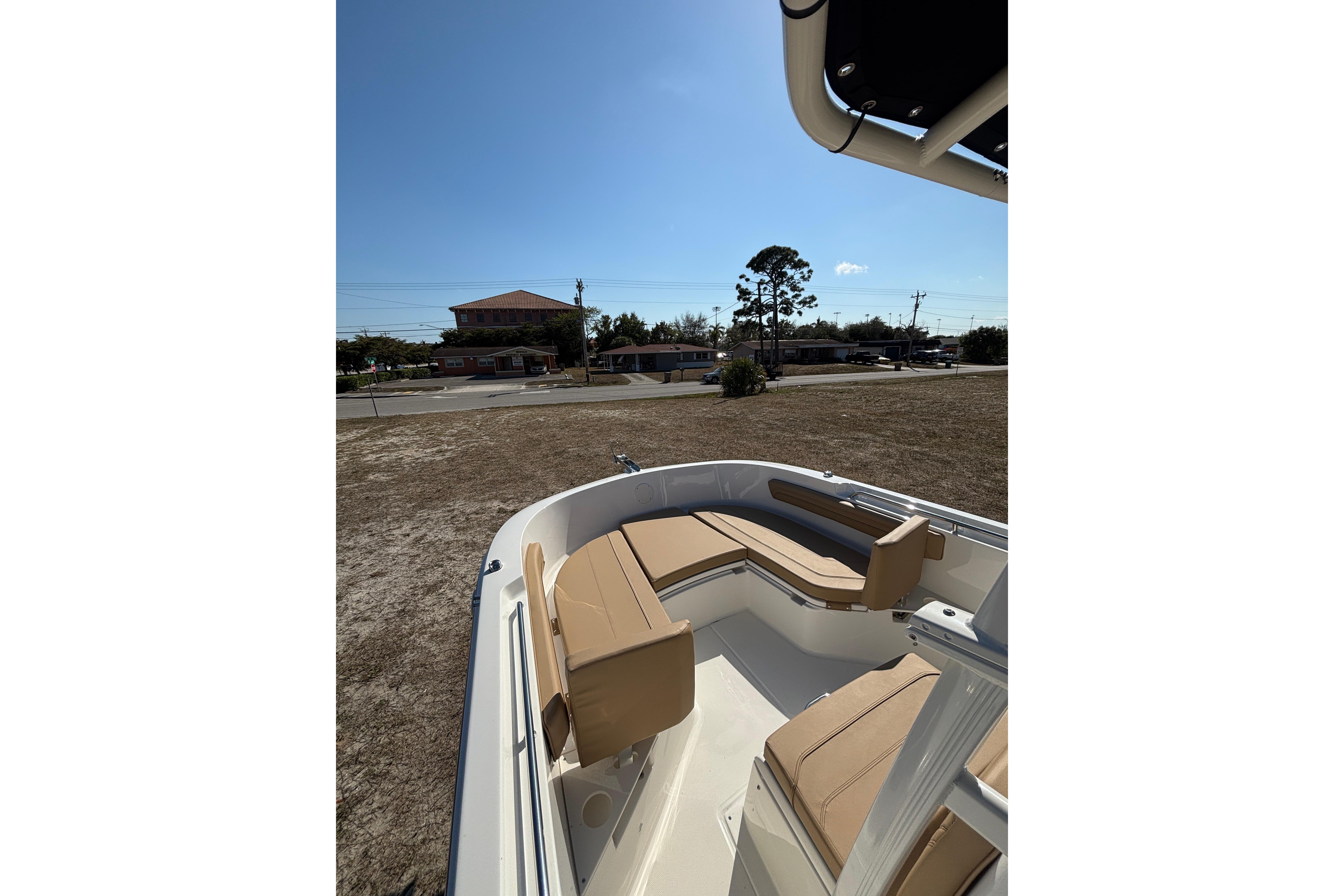 2026 Bayliner Trophy T22CC boat with tan seating, parked on dry land under clear blue sky.
