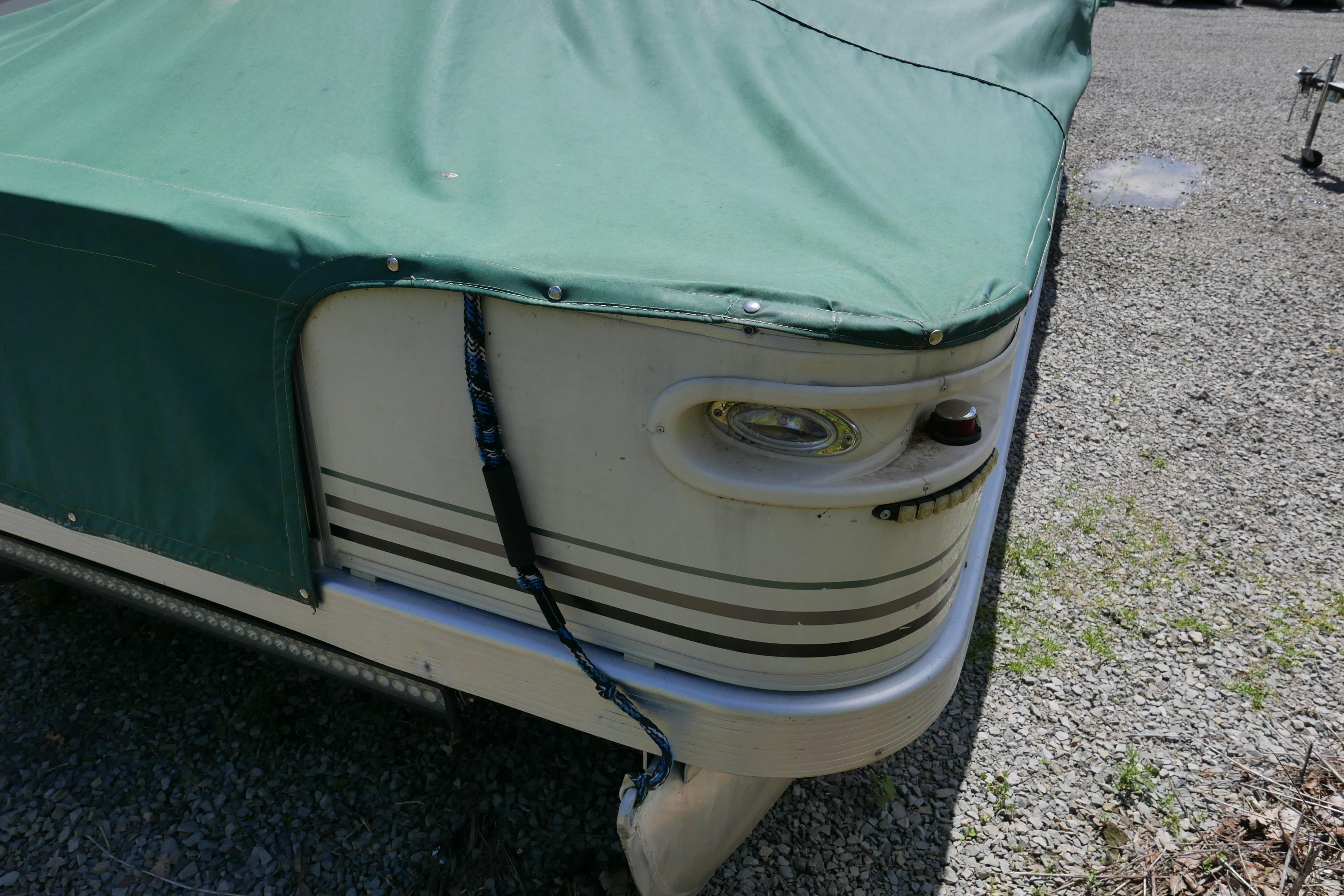 2005 Bennington 257FS boat with green cover on gravel surface.