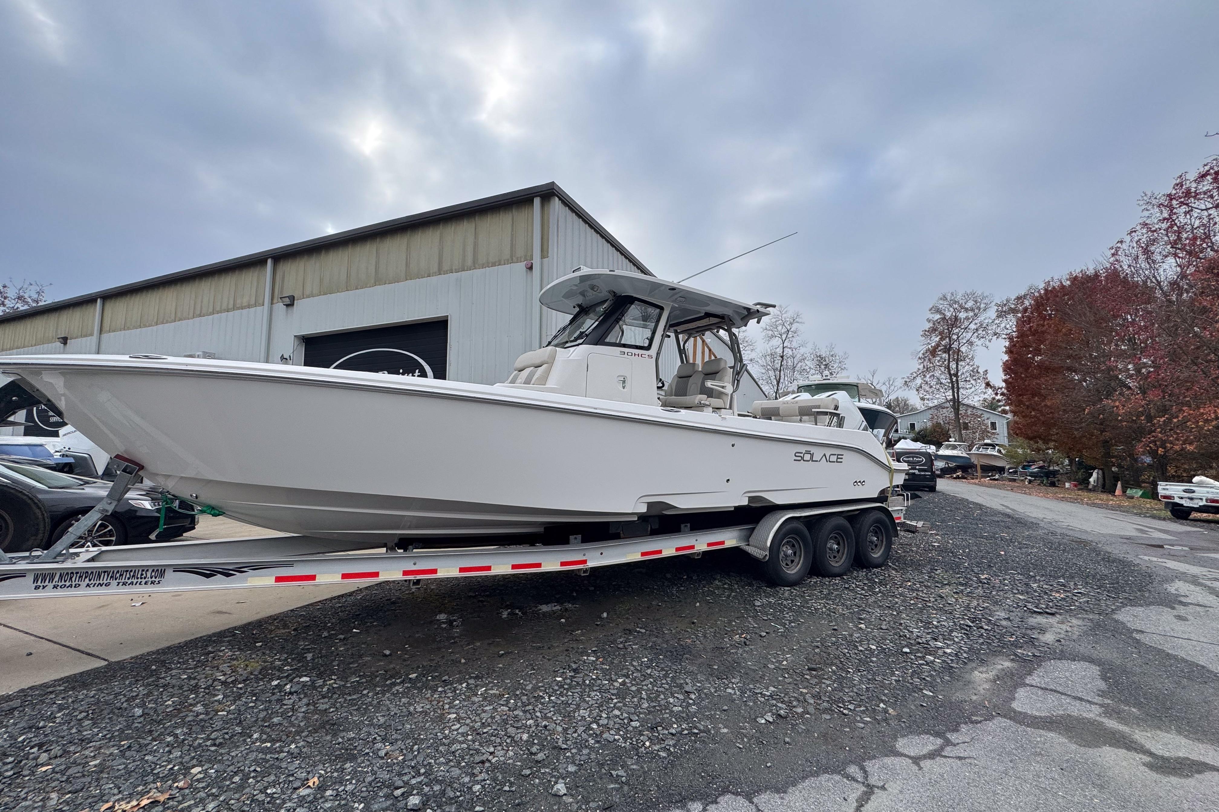 2025 Solace 30 HCS boat on trailer outside a warehouse, under cloudy sky.