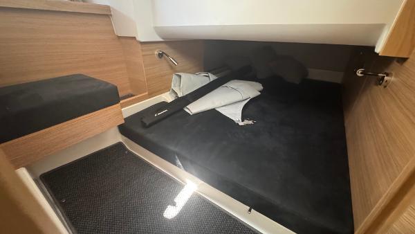 Cozy cabin interior of 2025 Nimbus T11 boat with wooden accents and black bedding.