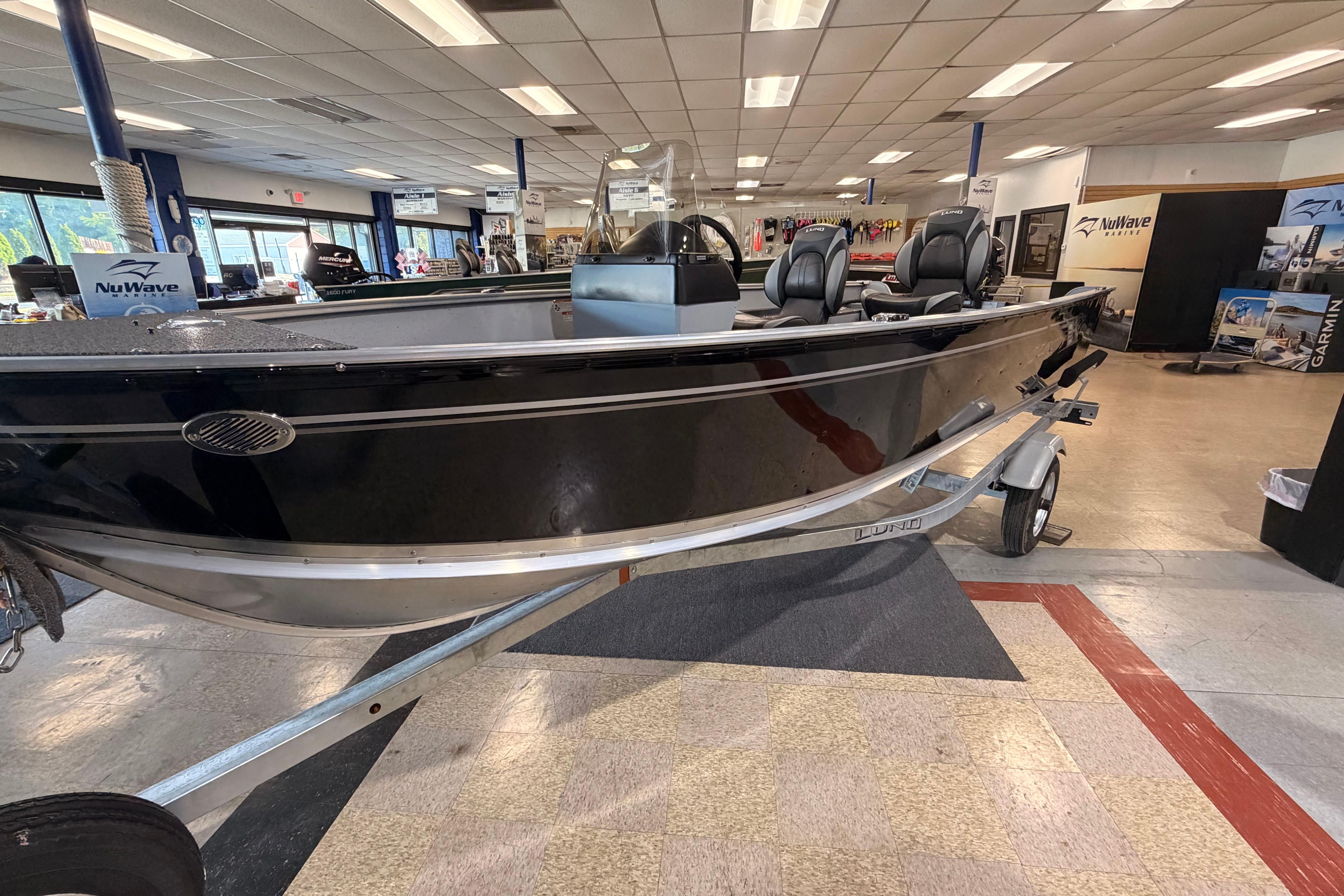 2027 Lund 1600 Fury SS boat displayed in showroom, featuring sleek black design and modern seating.