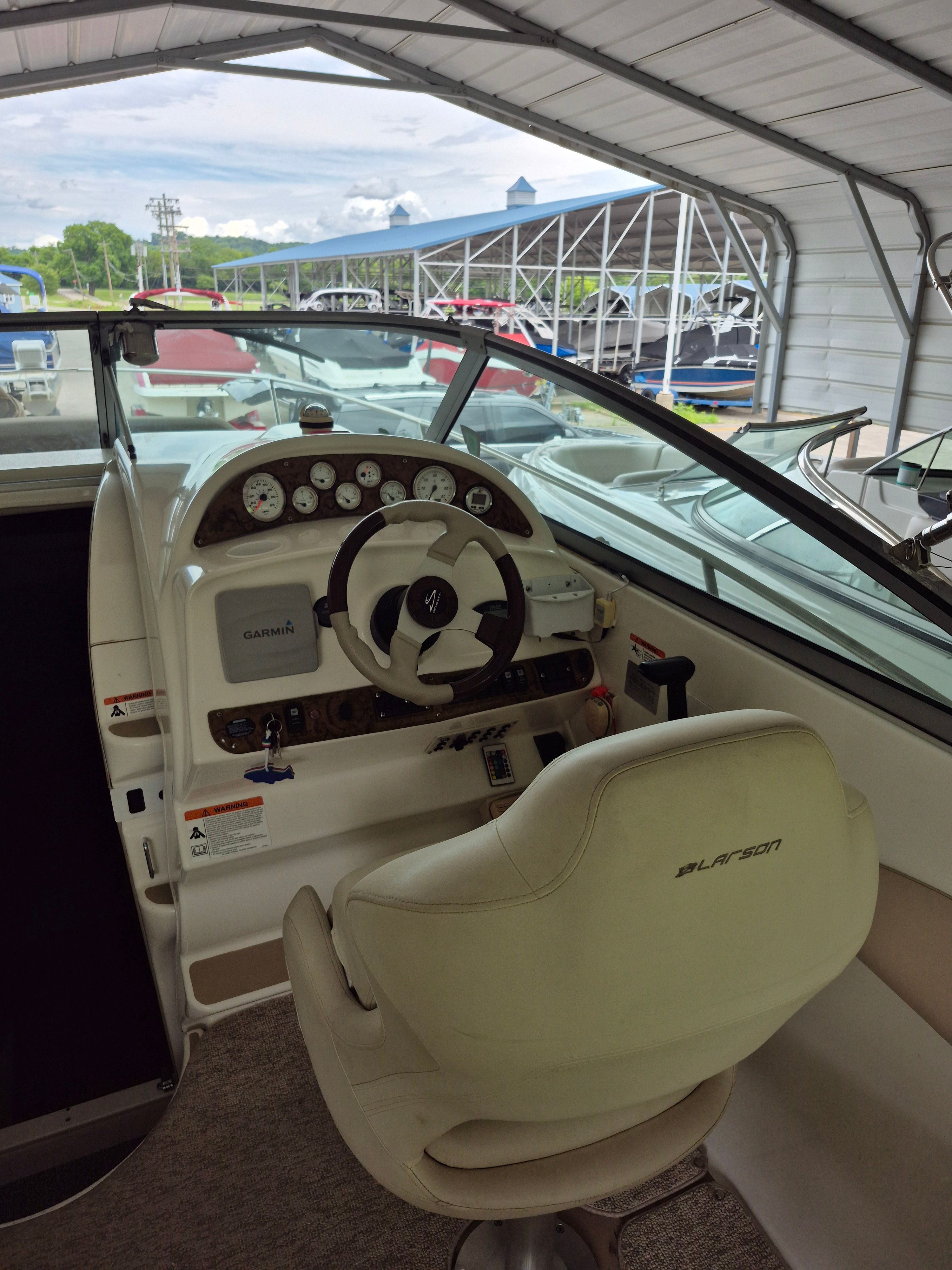 The image shows the cockpit of a 2004 Larson Cabrio 274 with a white steering wheel and instruments.