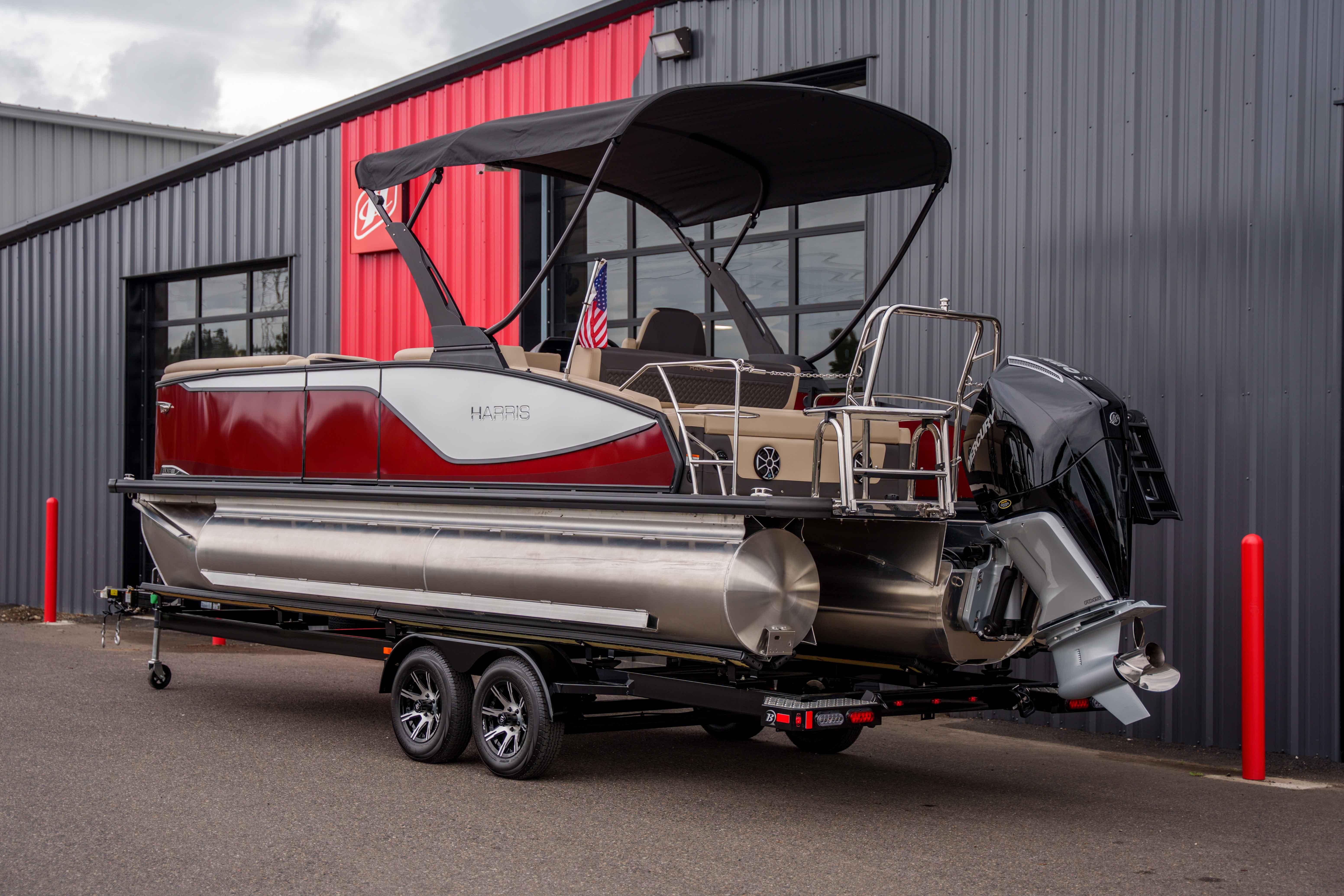 2026 Harris Sunliner 230 pontoon boat on trailer, parked outside a modern building.