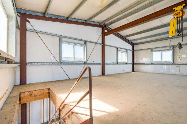 Spacious interior of 1985 Custom Larson Boathouse with metal beams and windows.