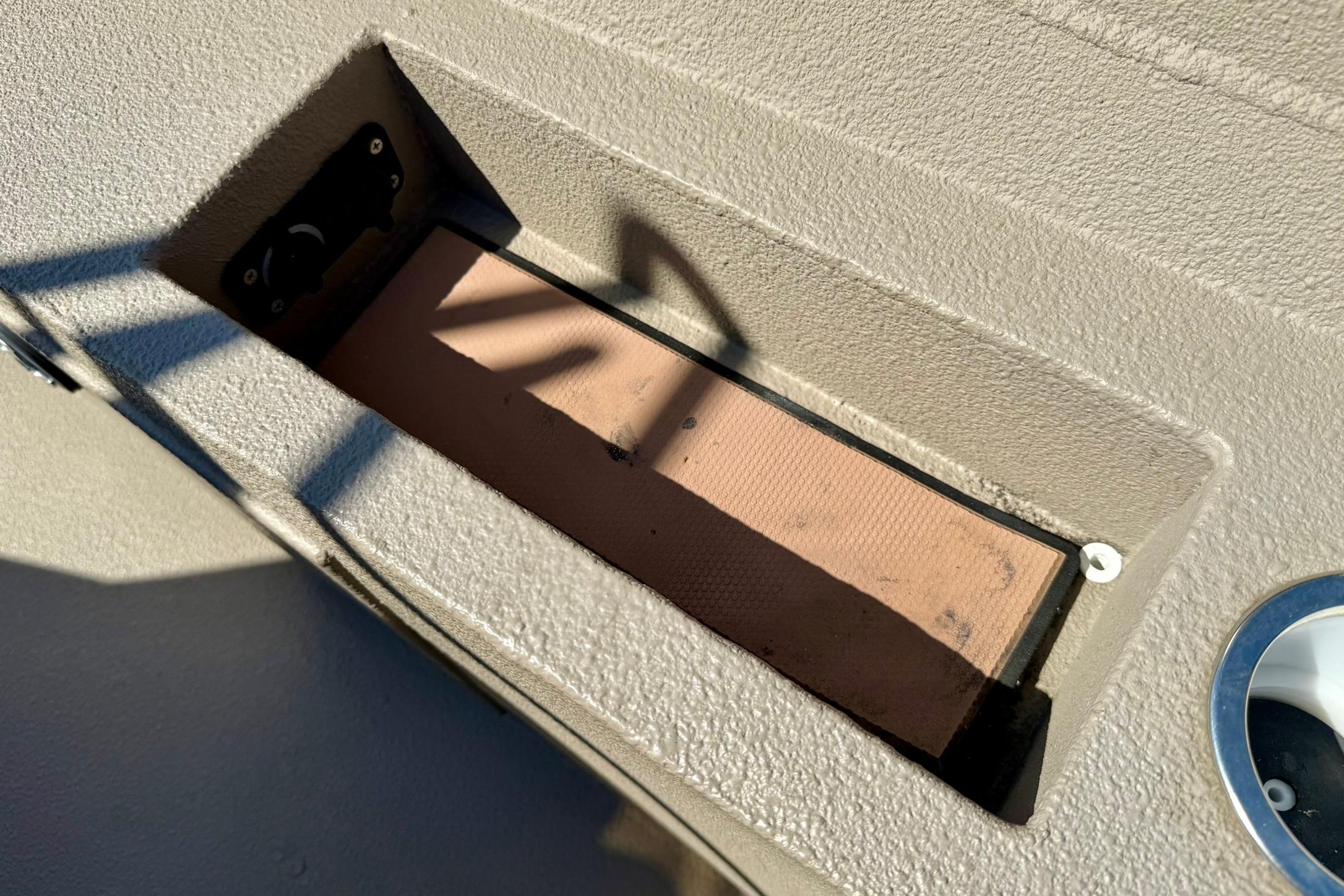 2019 Excel 230 Bay Pro boat compartment with textured surface and shadow details.