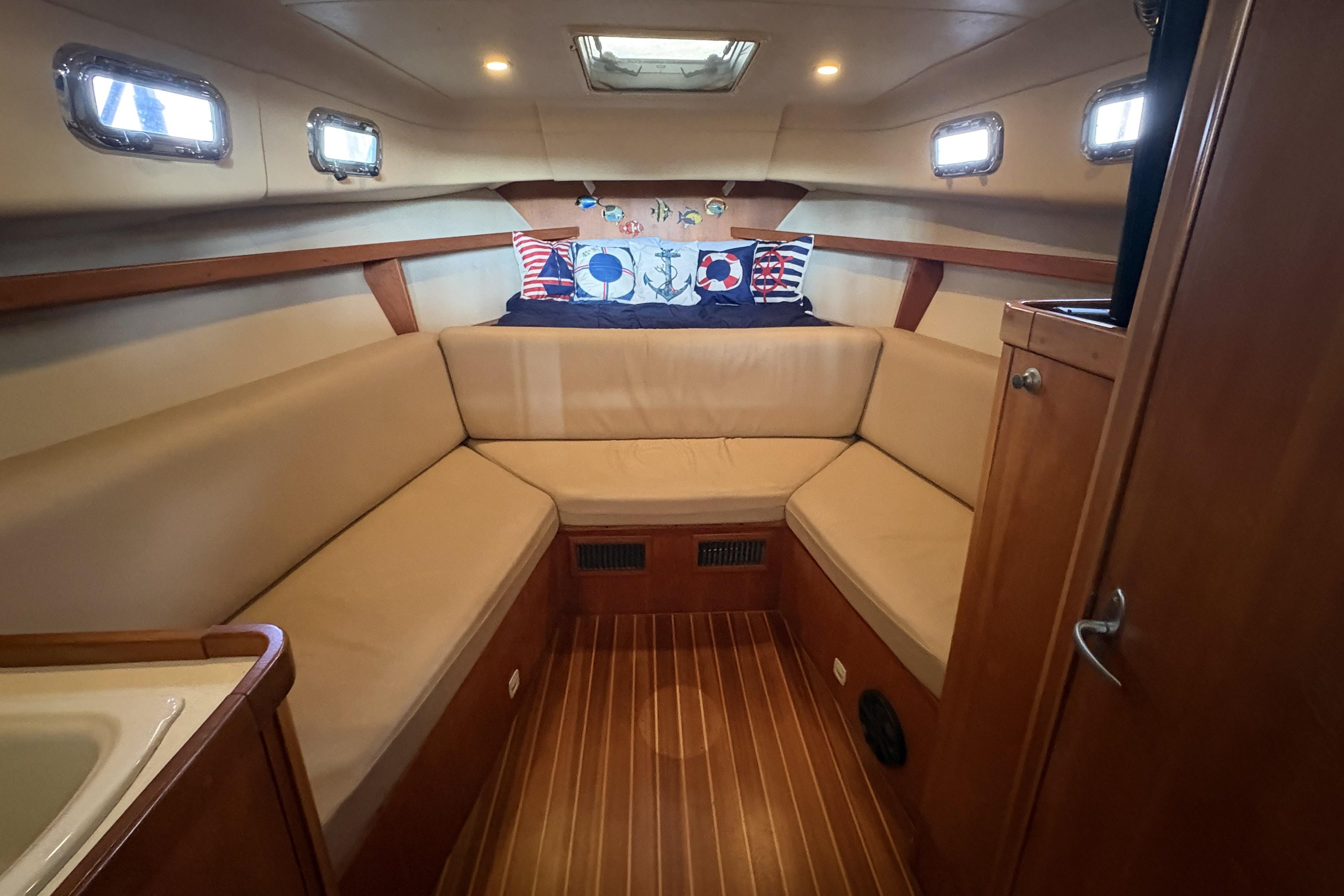 2003 Mainship Pilot 30-II cabin interior with beige seating and nautical-themed decor.