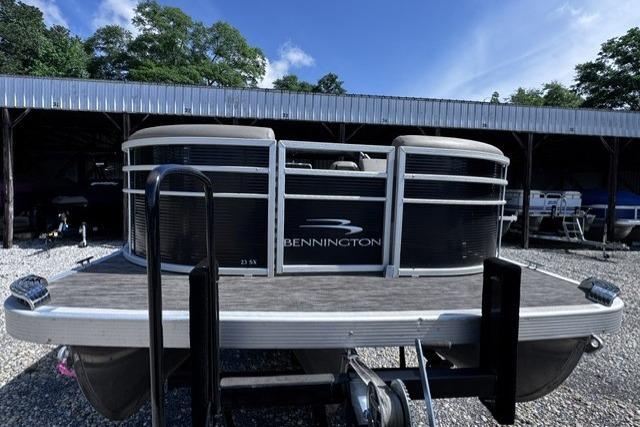 2021 Bennington 23 SSRX pontoon boat parked in a gravel lot under a clear blue sky.