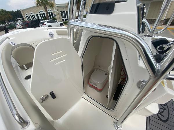 2024 Key West 203 FS boat interior with open storage compartment and portable toilet.