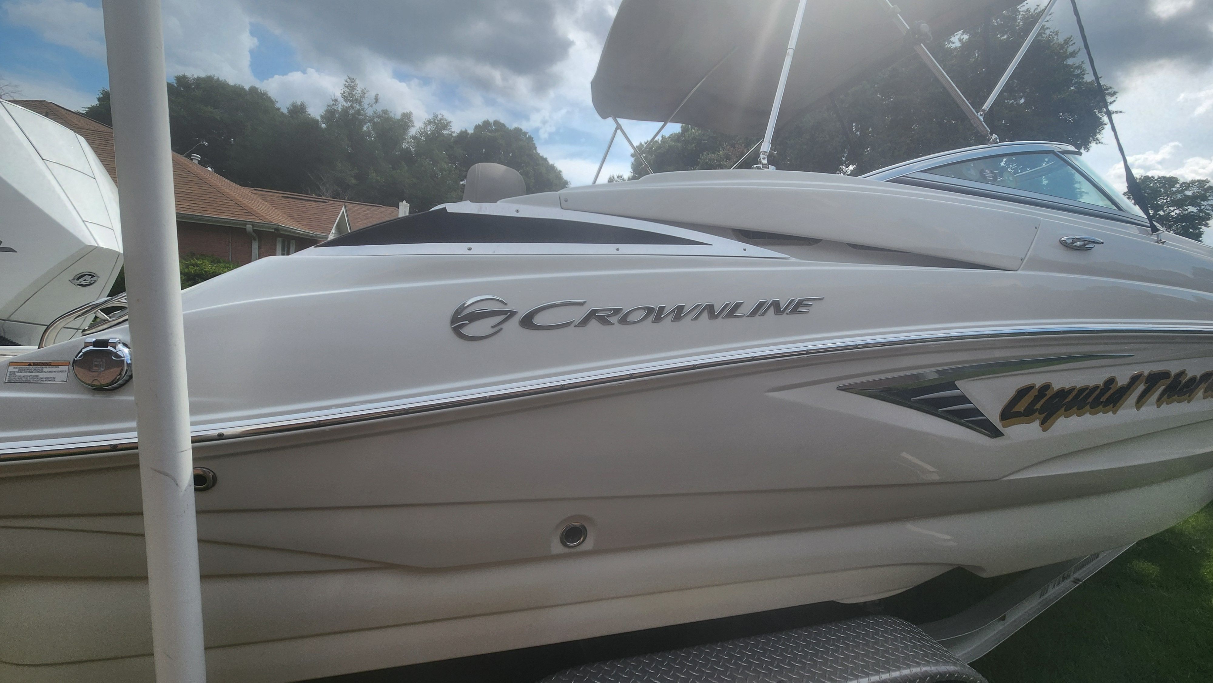 A white 2019 Crownline Eclipse E235 XS boat on a trailer under a cloudy sky.