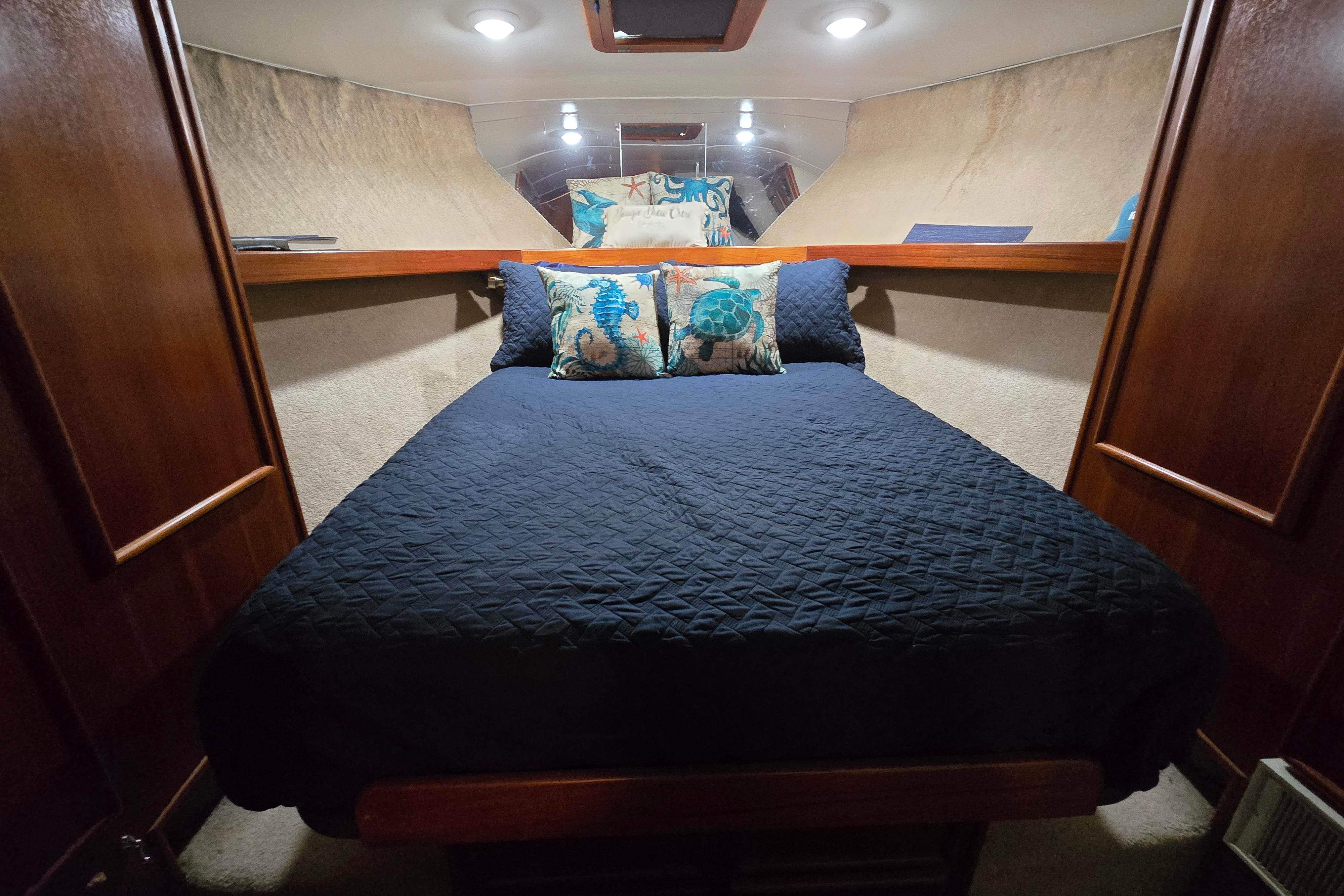 Cozy cabin interior of 1988 Post 46 Convertible with navy bedding and decorative pillows.