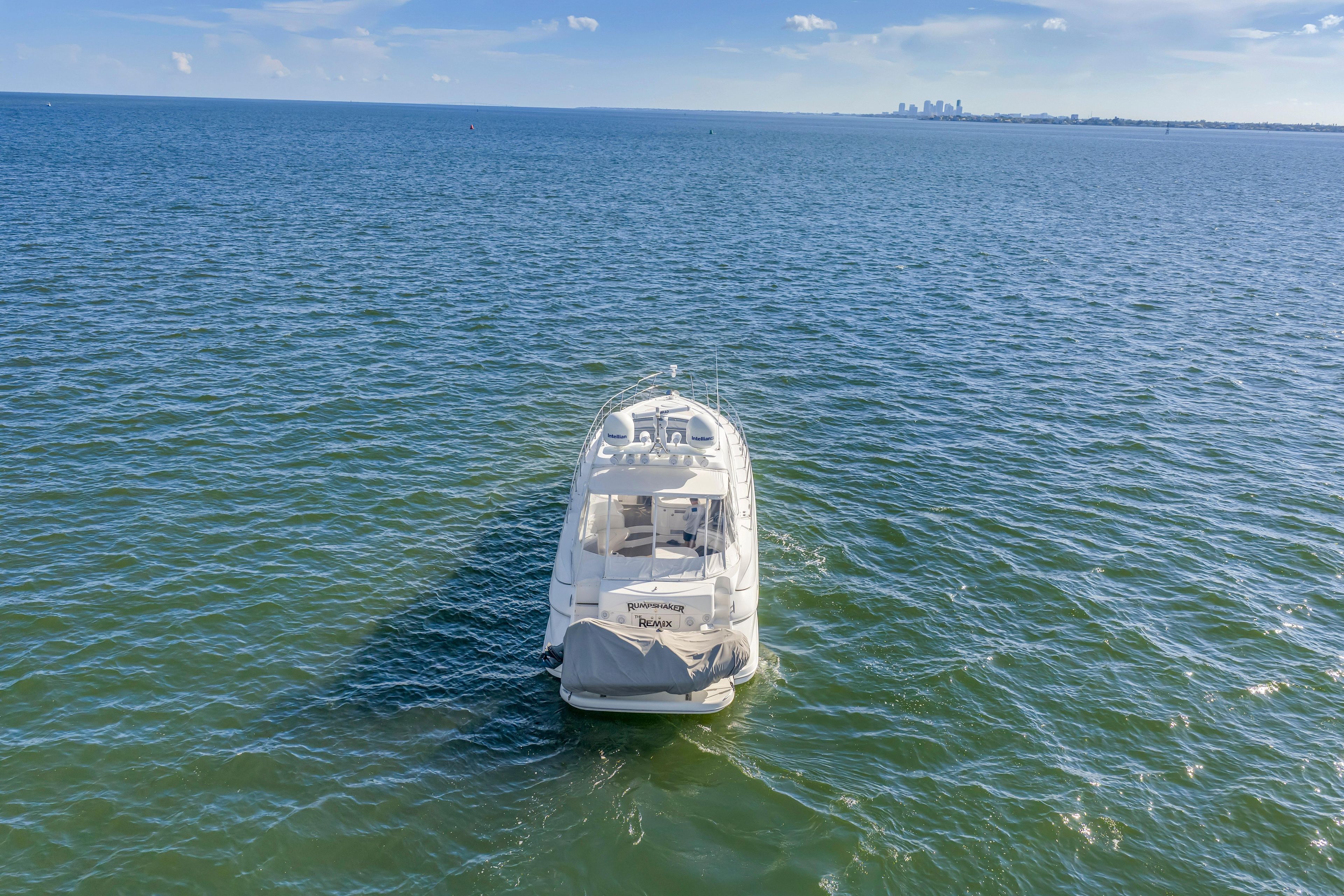 2002 Cruisers 5370 yacht on open water with distant city skyline.