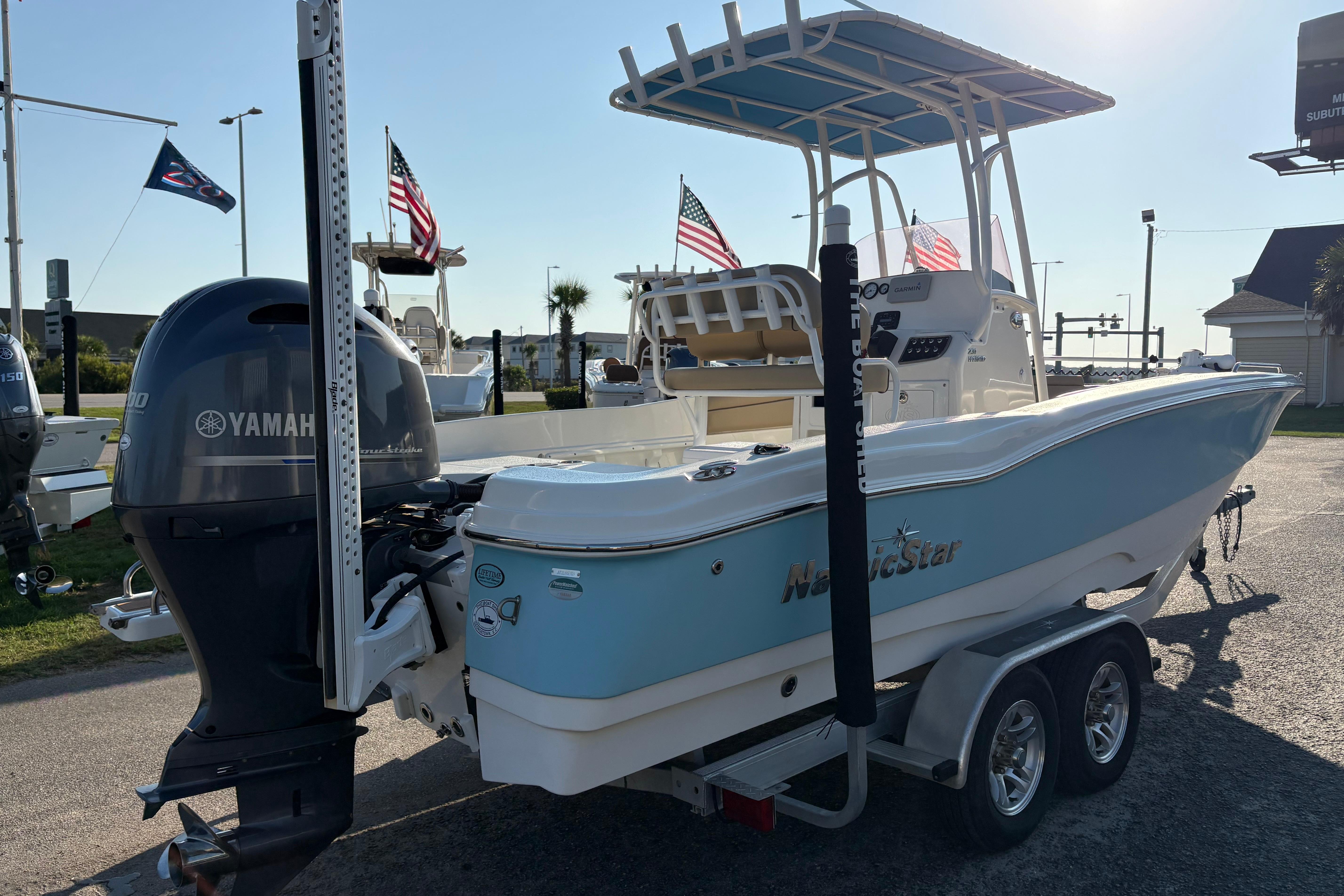2019 NauticStar 231 Hybrid boat with Yamaha engine on trailer, flags in background.
