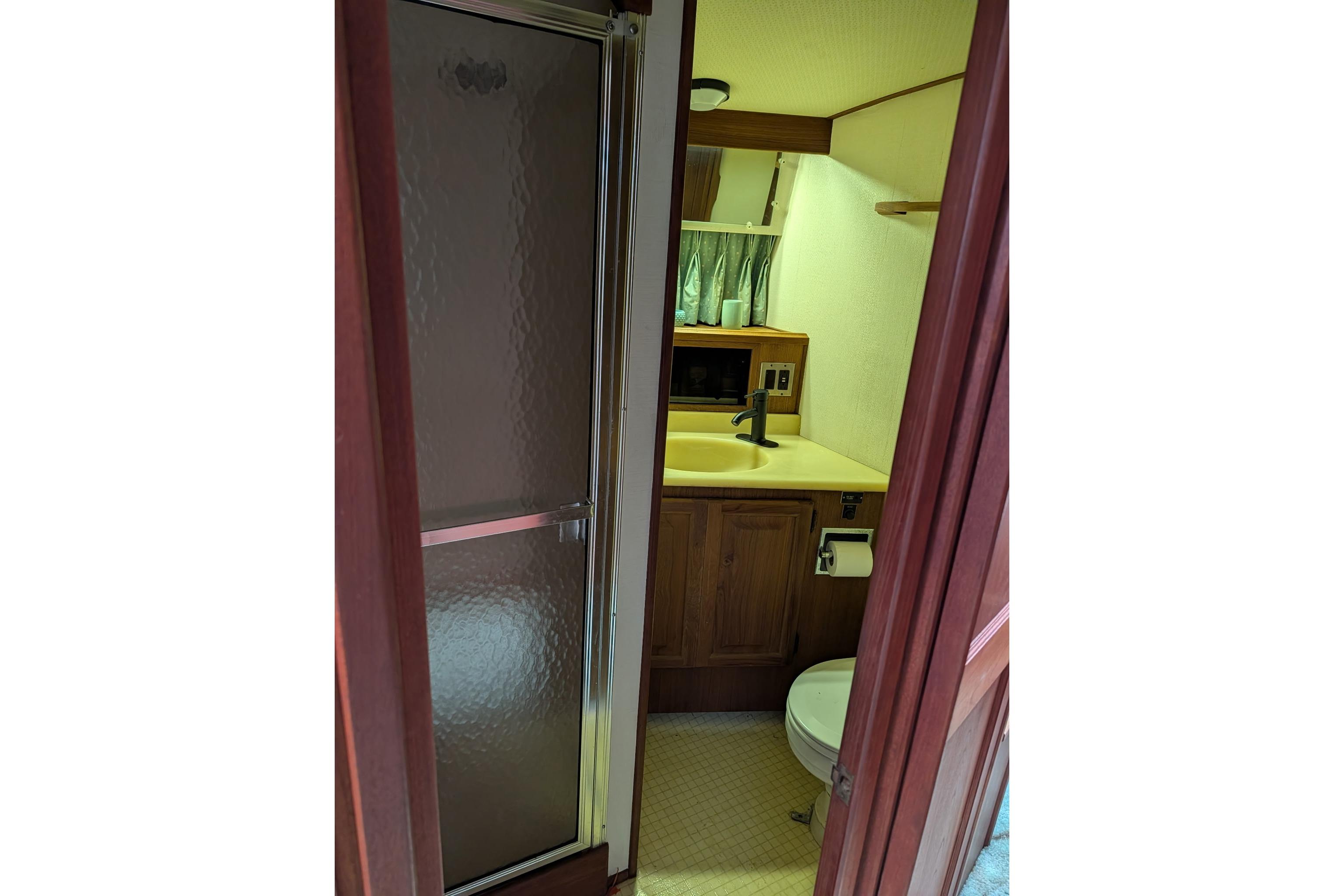 Bathroom interior of 1986 Viking Sportfish 41 yacht, featuring shower, sink, and toilet.