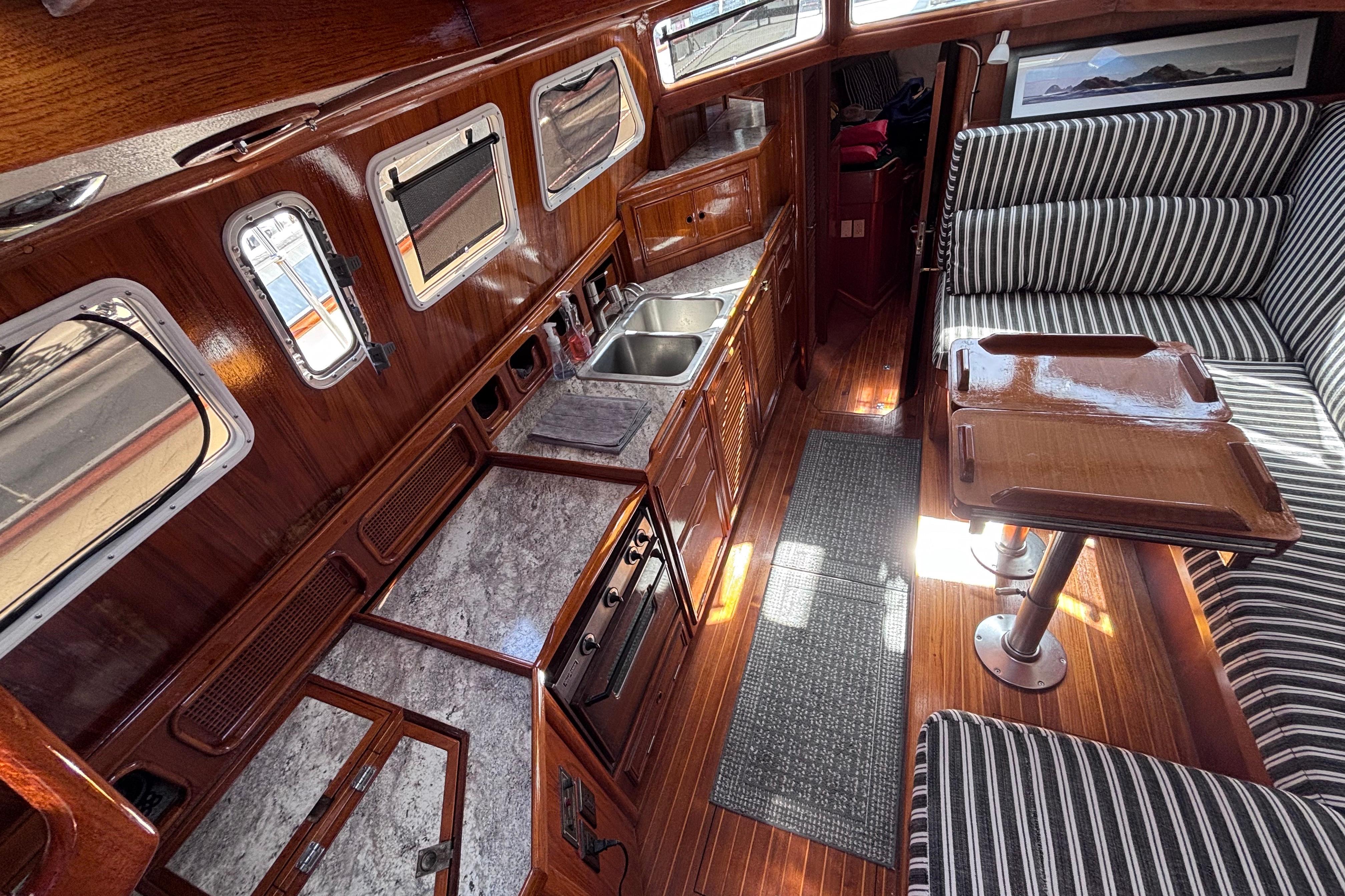 Interior of a 1978 Swift 33 boat featuring a wooden kitchen and striped seating.