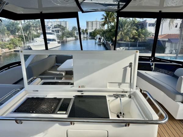 Luxury Aquila 44 yacht interior with kitchenette, overlooking marina and palm trees, 2022 model.