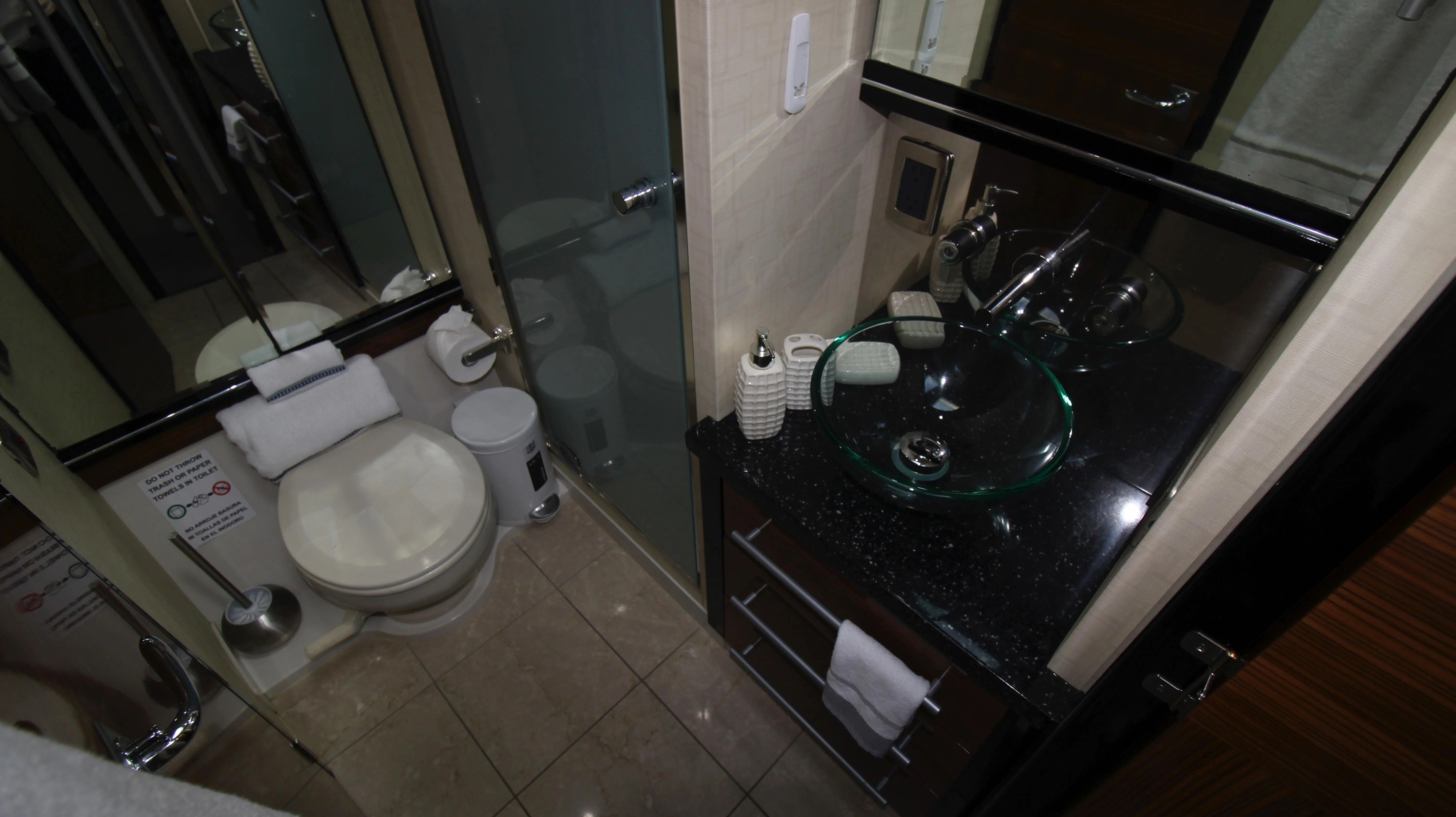 The bathroom of a 2010 Marquis Sport Coupe with a glass sink and toilet.