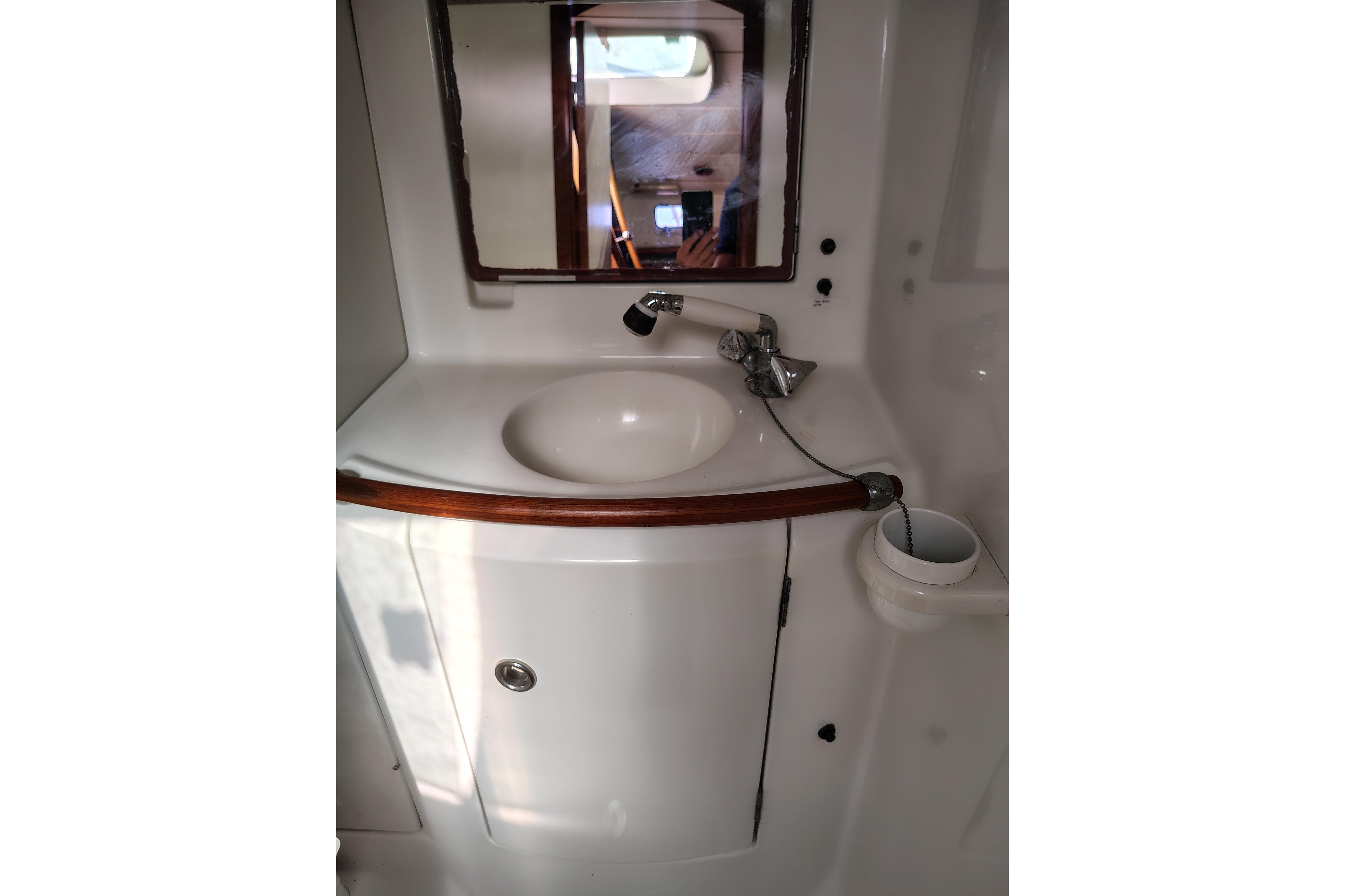 Bathroom sink area in a 2001 Beneteau Oceanis 411 yacht, featuring a mirror and faucet.
