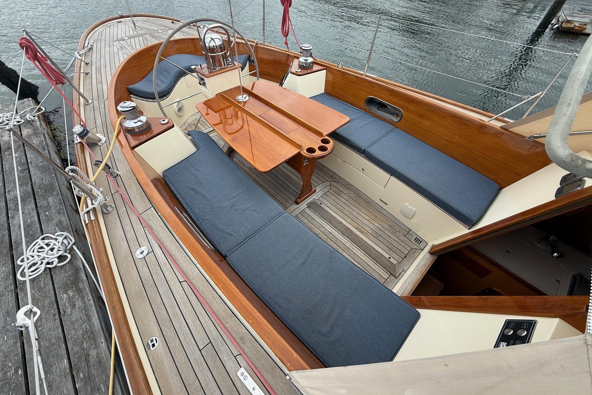 Hinckley DS 42 sailboat cockpit with wooden table and blue cushions, docked by the water.