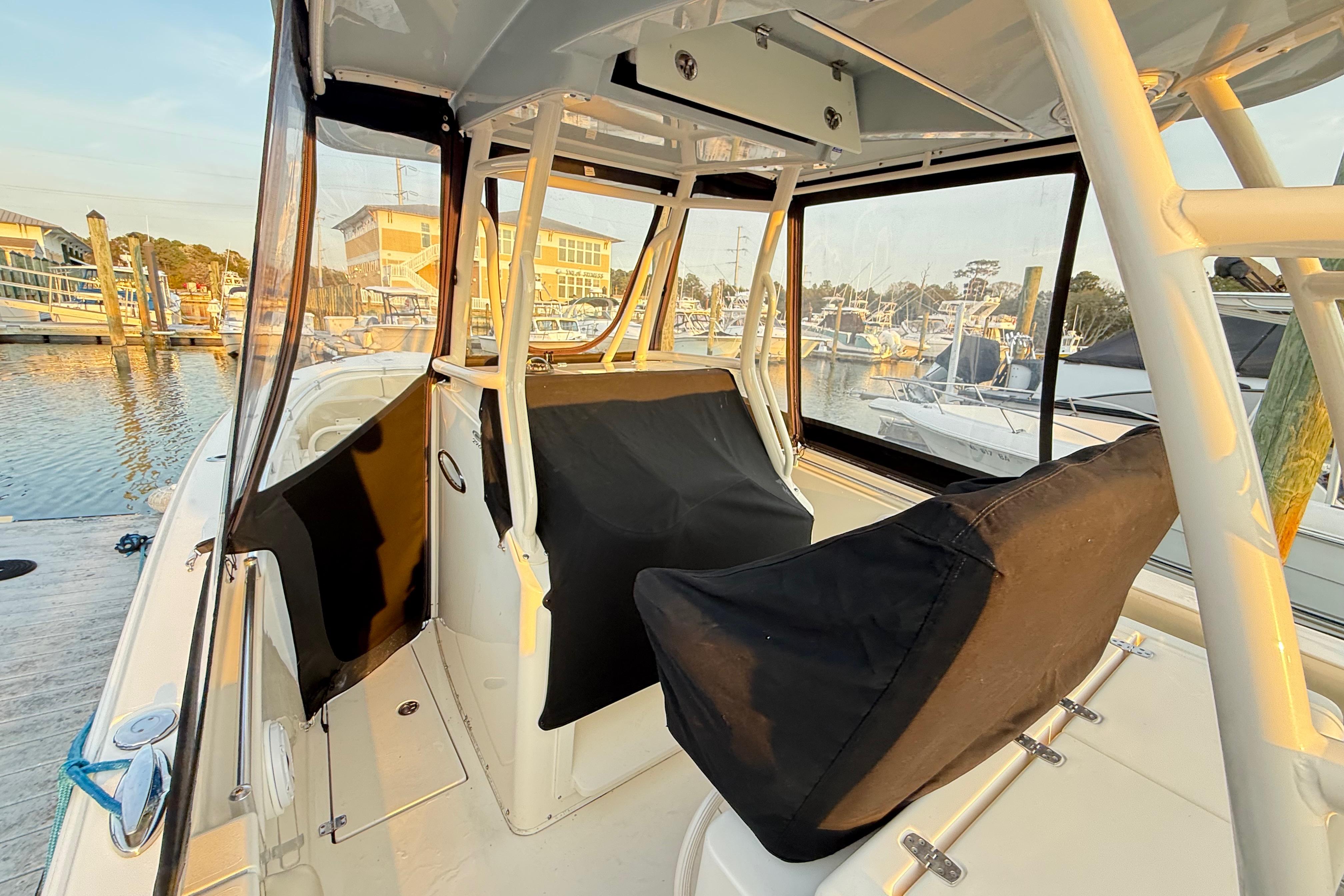 2016 Cobia 296 Center Console boat interior at marina, featuring covered seating and helm.