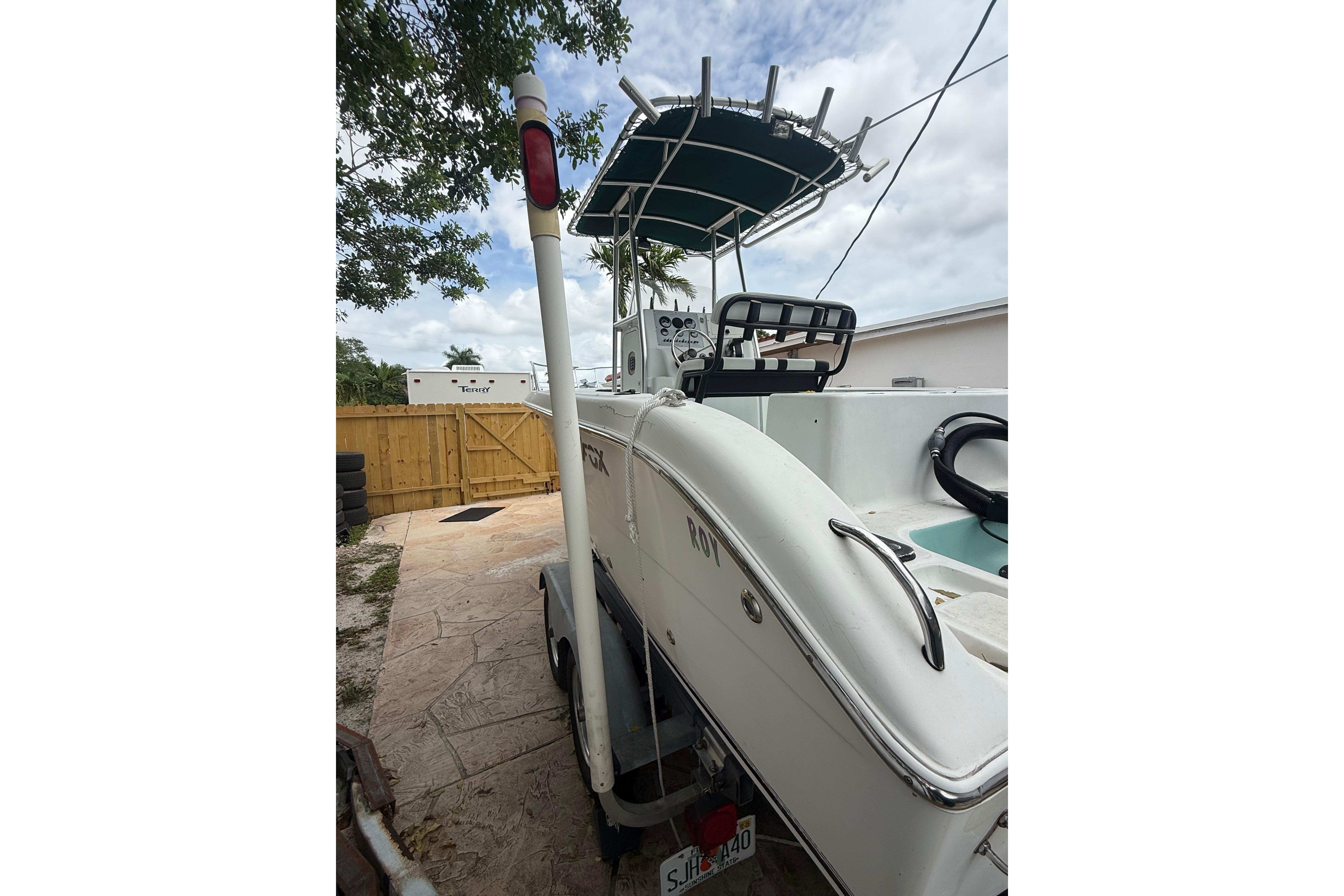 2005 LYG Sea Fox boat parked in driveway, featuring a T-top and steering console.