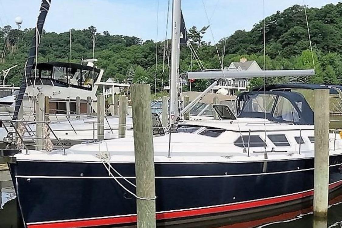2007 Hunter 41 Deck Salon sailboat docked at a marina, surrounded by lush greenery.