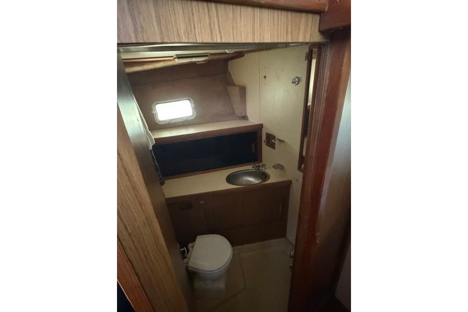 1980 Chris-Craft 381 Catalina yacht bathroom with sink, toilet, and window.