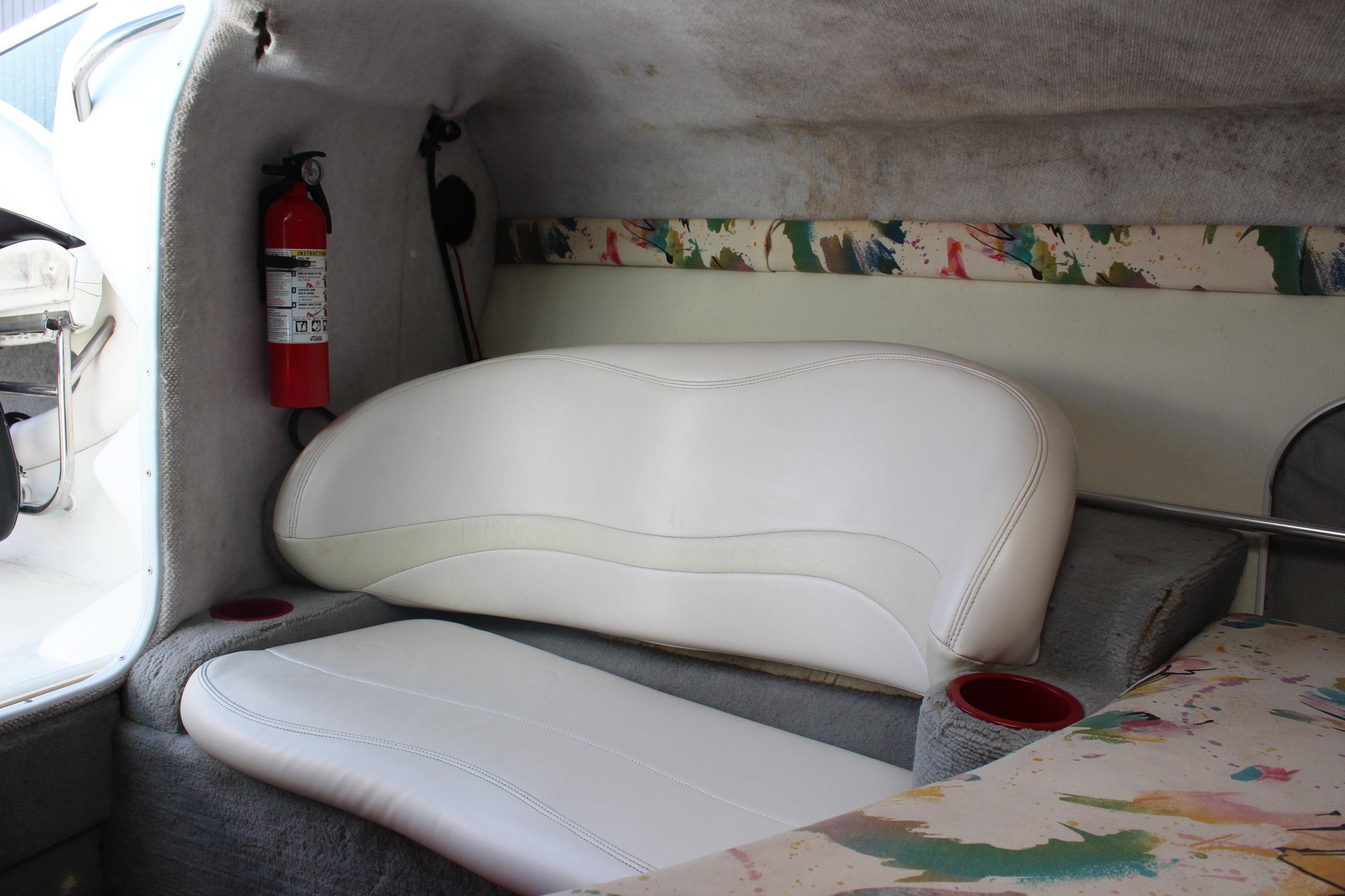 Interior of a 1996 Baja 232 boat with white seating and a fire extinguisher.