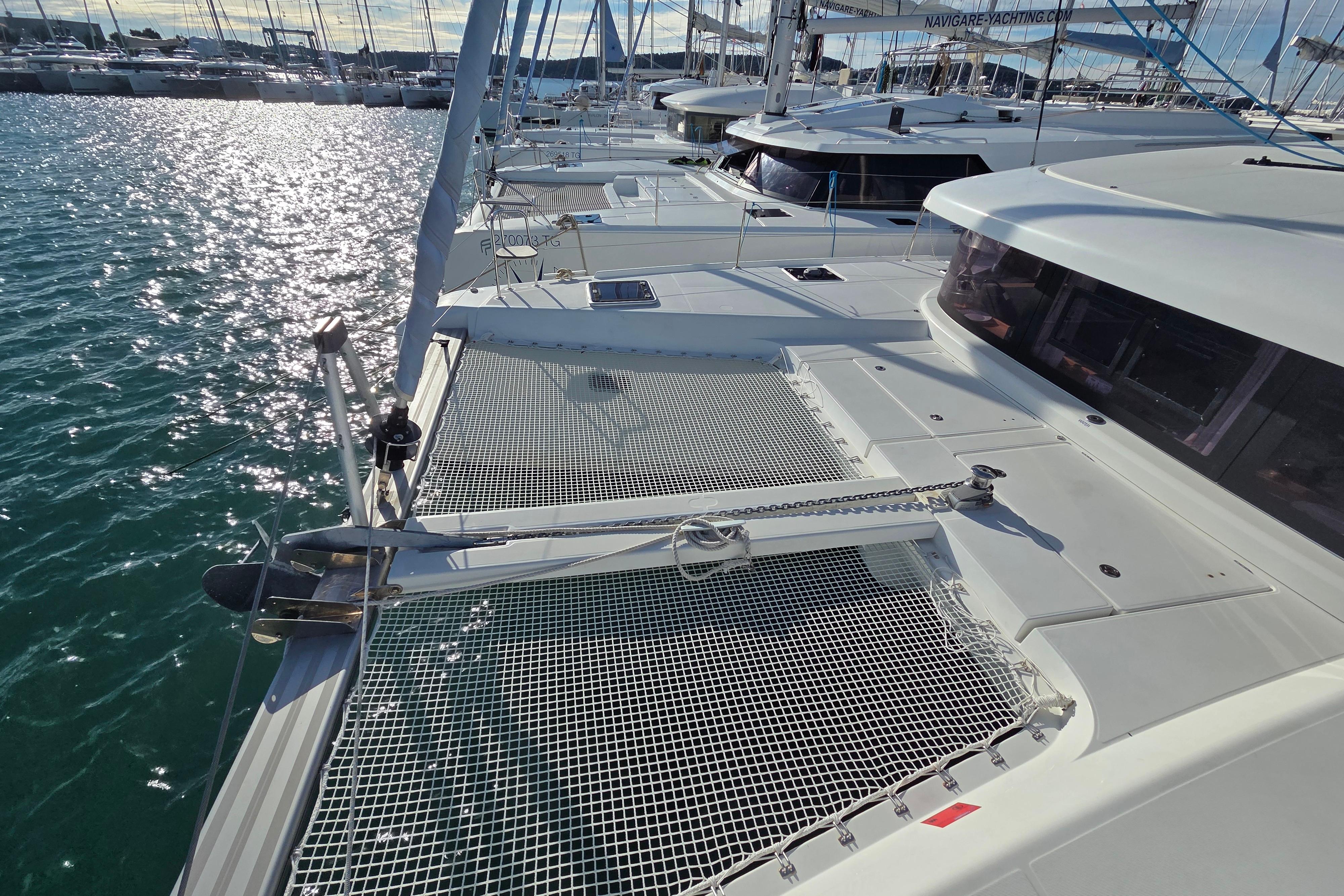 2018 Lagoon 42 catamaran docked in a marina, with sunlit water and multiple yachts.