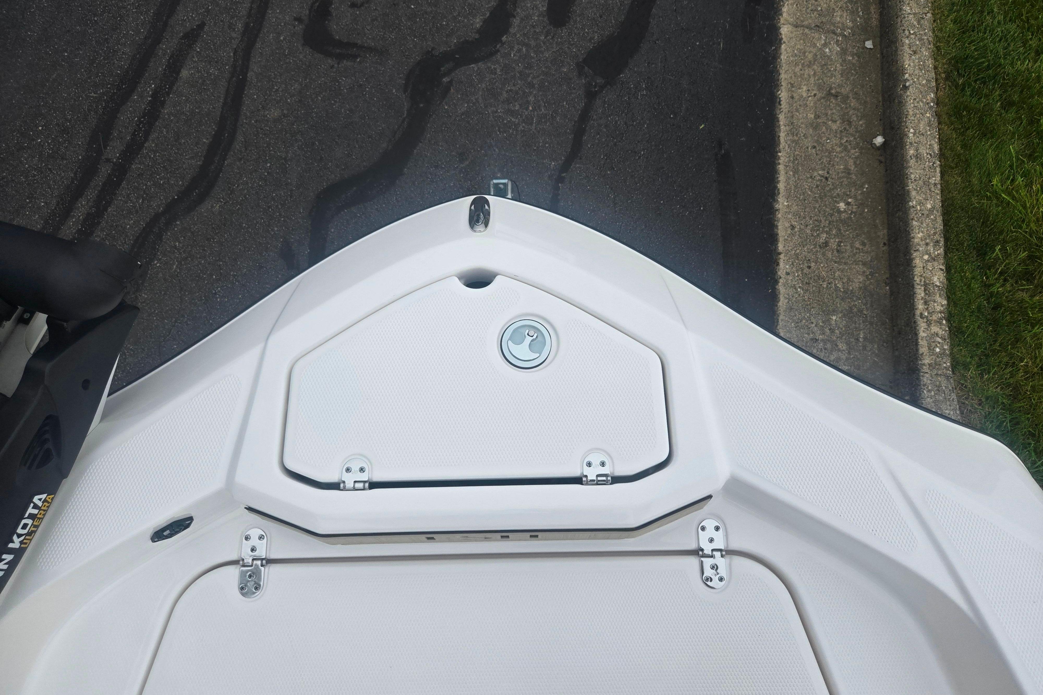 2022 Yamaha Boats 195 FSH Sport bow storage compartment, white finish, on pavement.