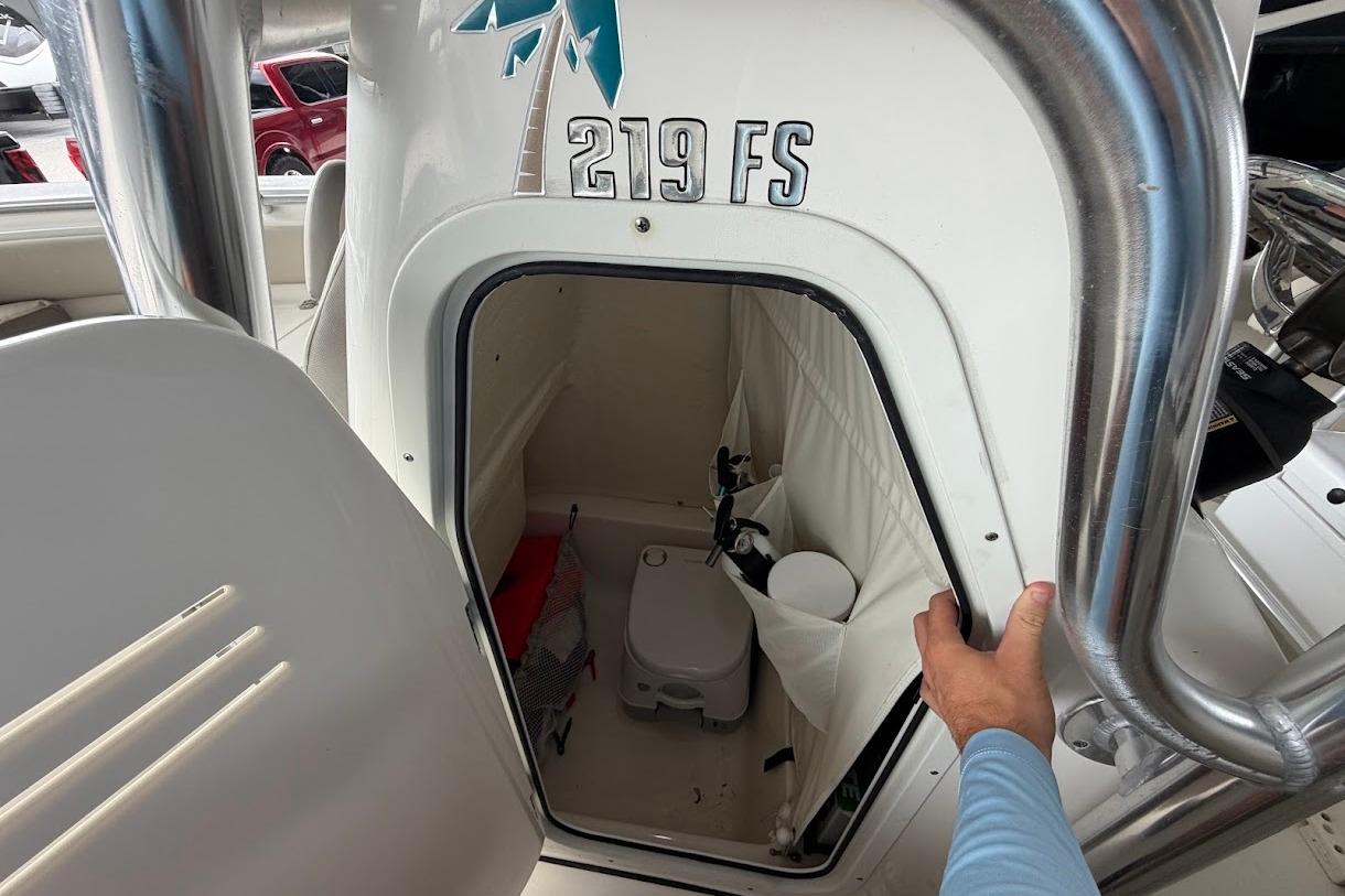 2024 Key West 219 FS boat interior with storage compartment and portable toilet.
