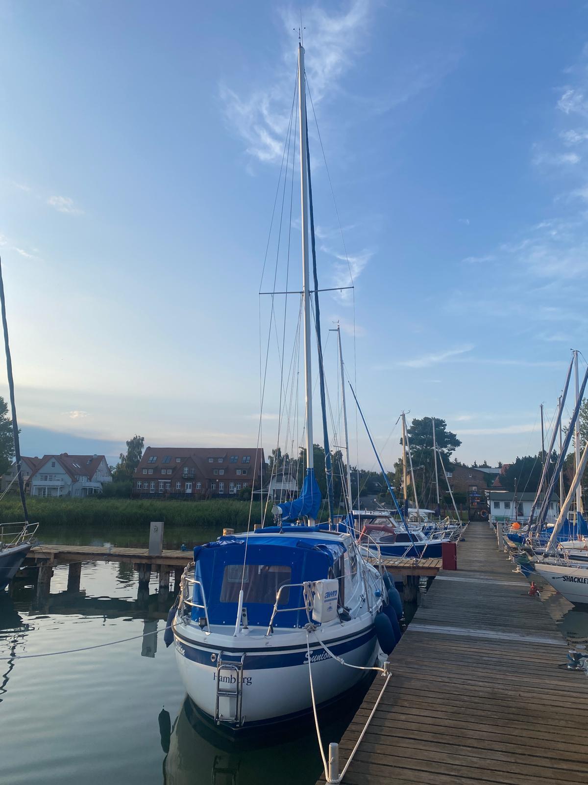 1980 LM 32 sailboat docked at a marina under a clear blue sky.