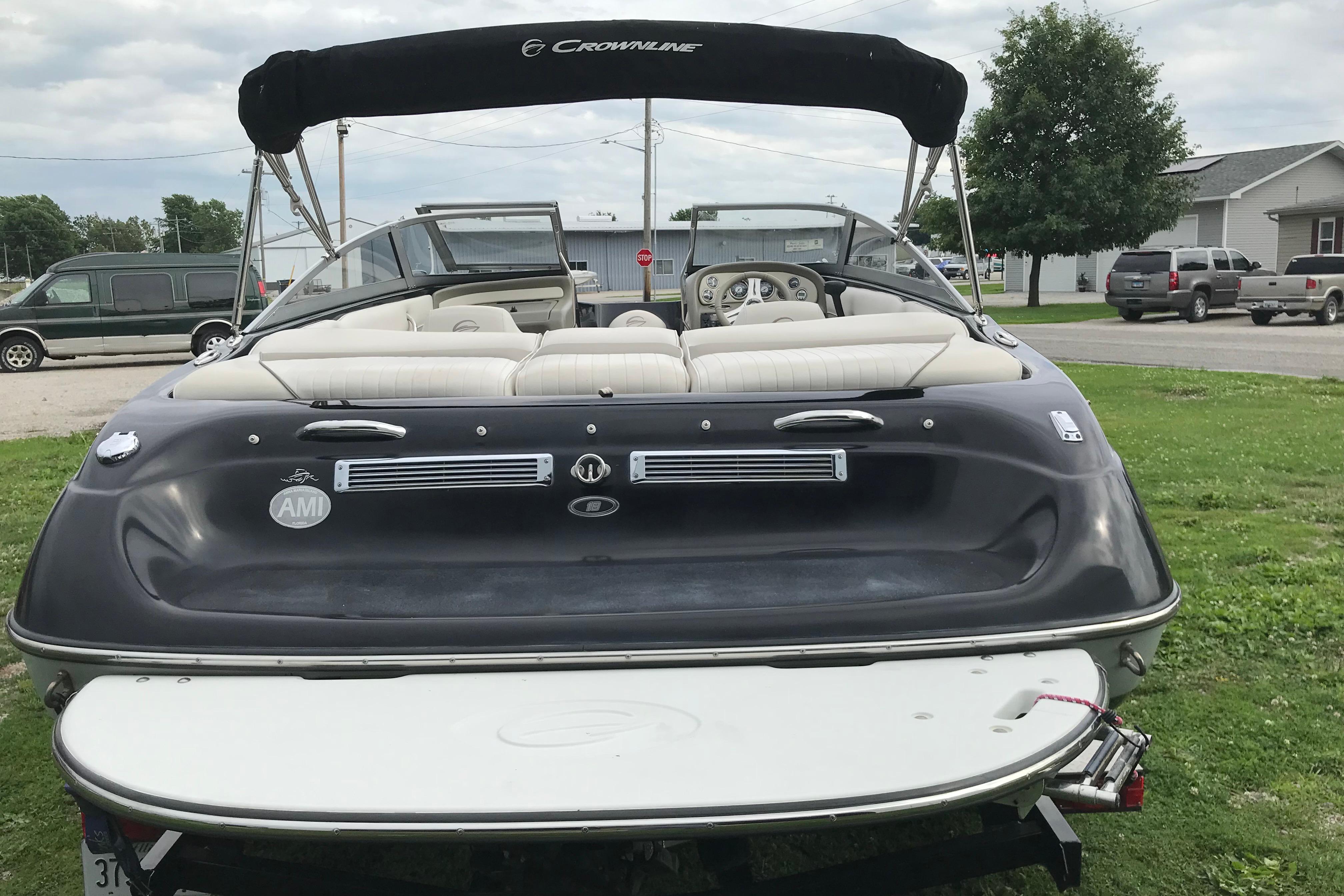 2015 Crownline 18 SS boat, rear view with seating and canopy, parked on grass.
