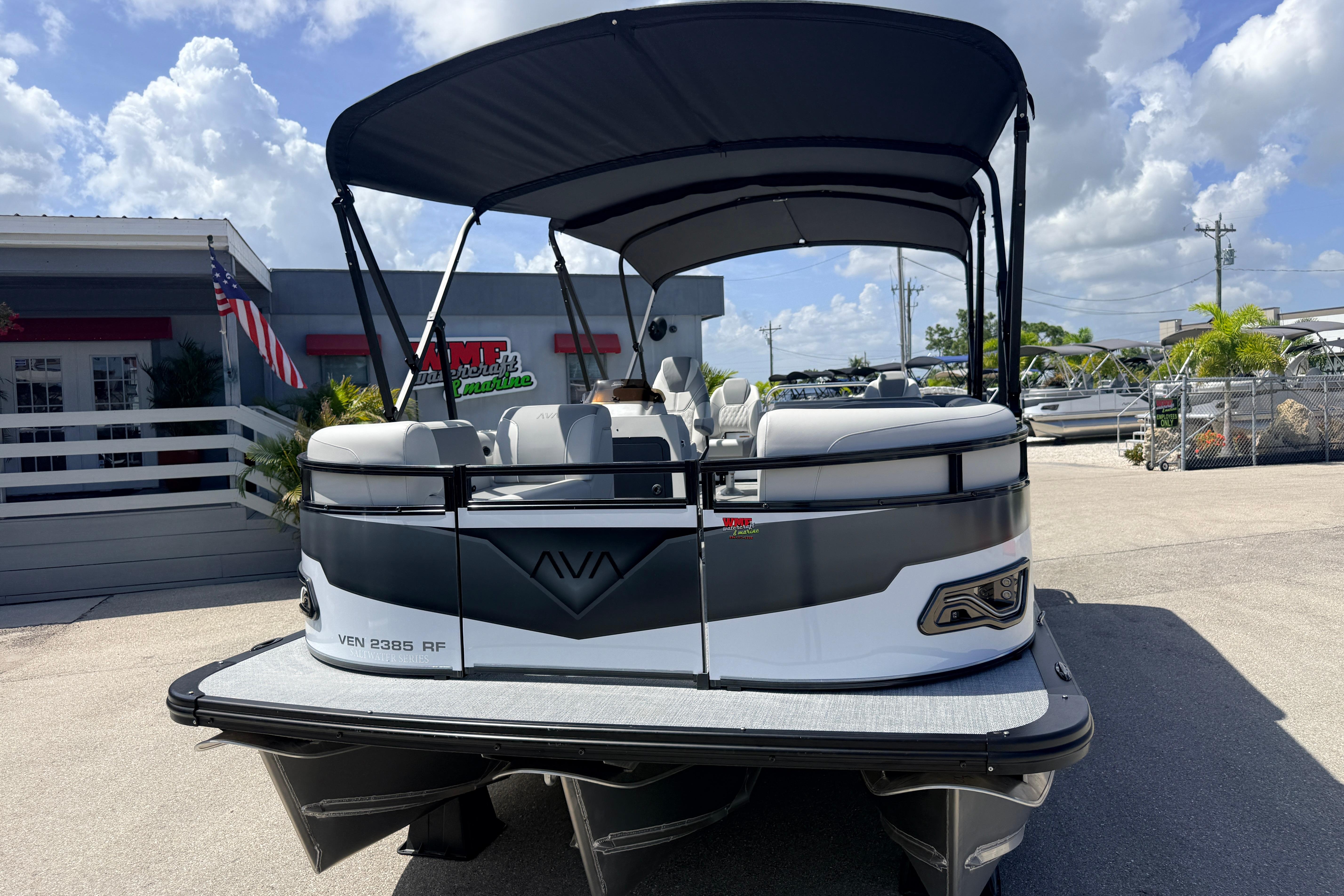 2026 Avalon 2385 Venture Tri Toon boat with canopy, parked outdoors under a blue sky.