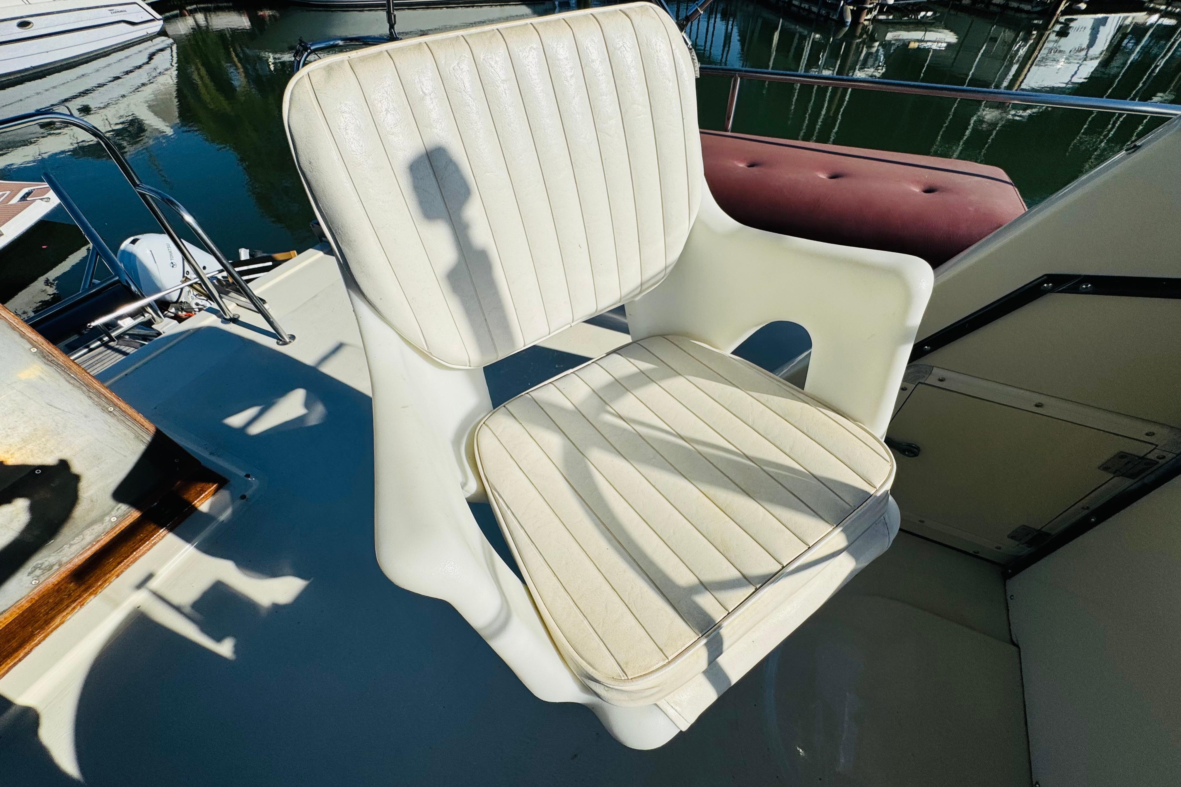 White captain's chair on a 1996 Nordic Tug 32 boat, docked at a marina.