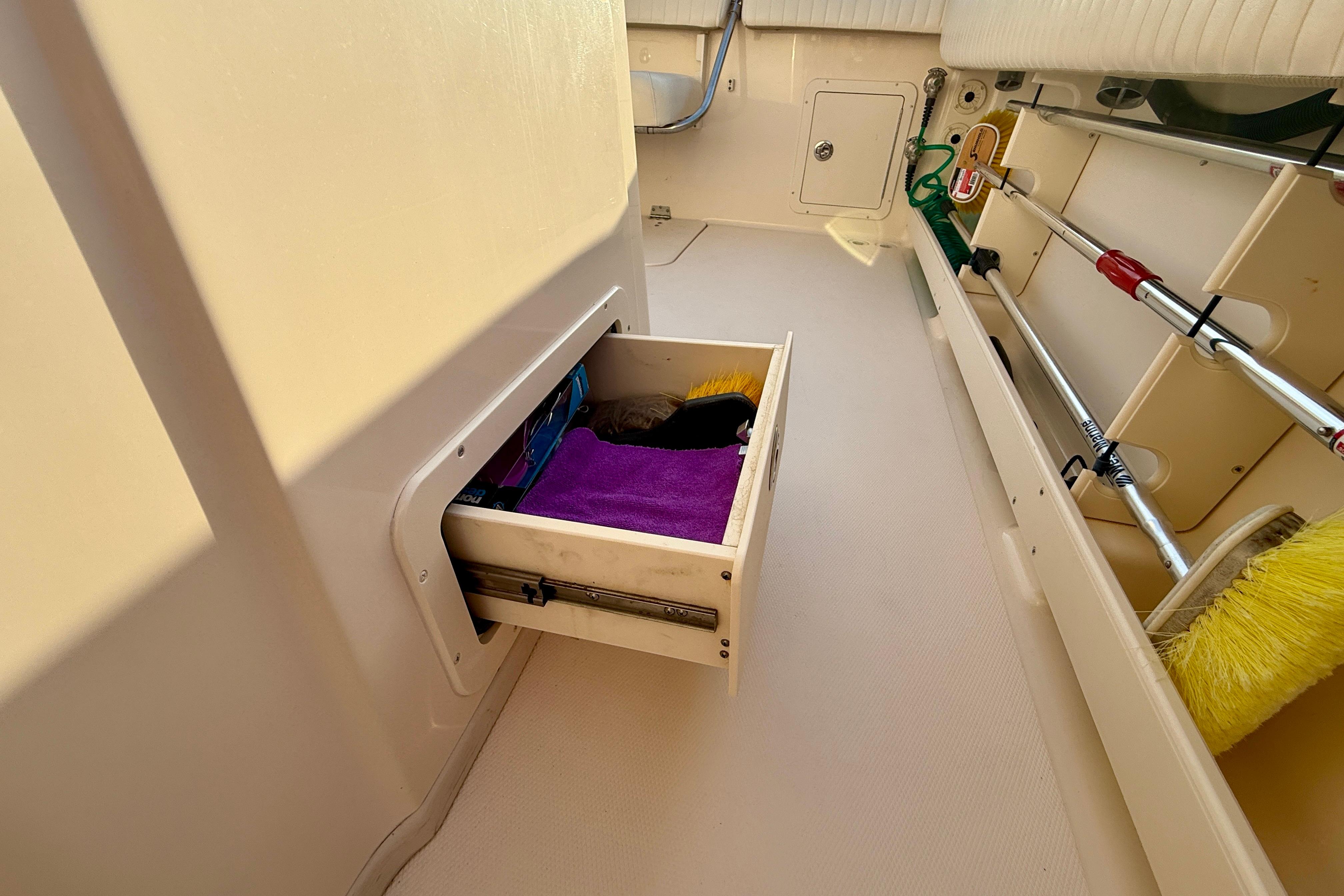 Storage drawer on 2012 Grady-White Canyon 336 boat, containing cleaning supplies and brushes.
