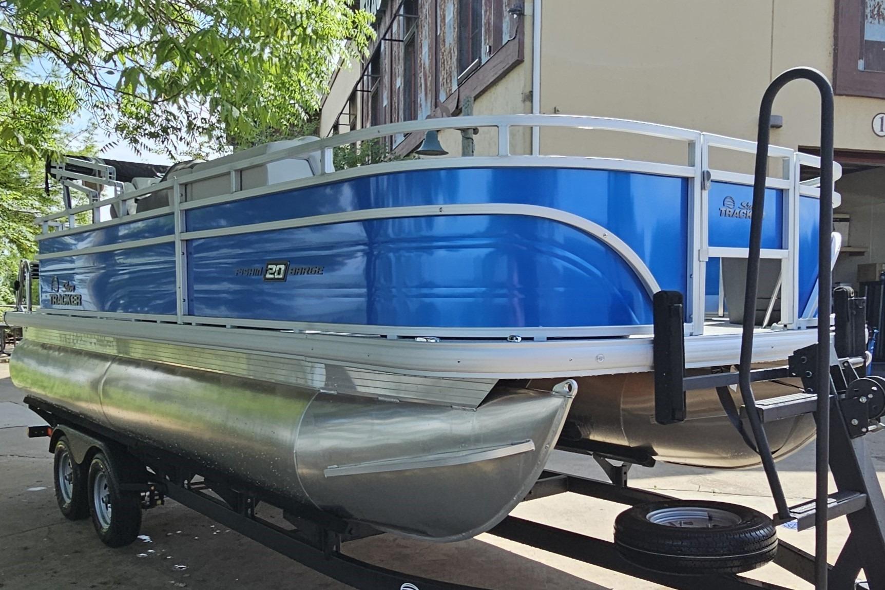 2026 Sun Tracker Fishin' Barge 20 DLX pontoon boat on trailer, blue exterior.