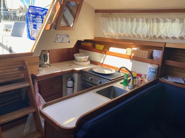 Interior of a 1989 Catalina 30 sailboat kitchen with wooden cabinetry and appliances.