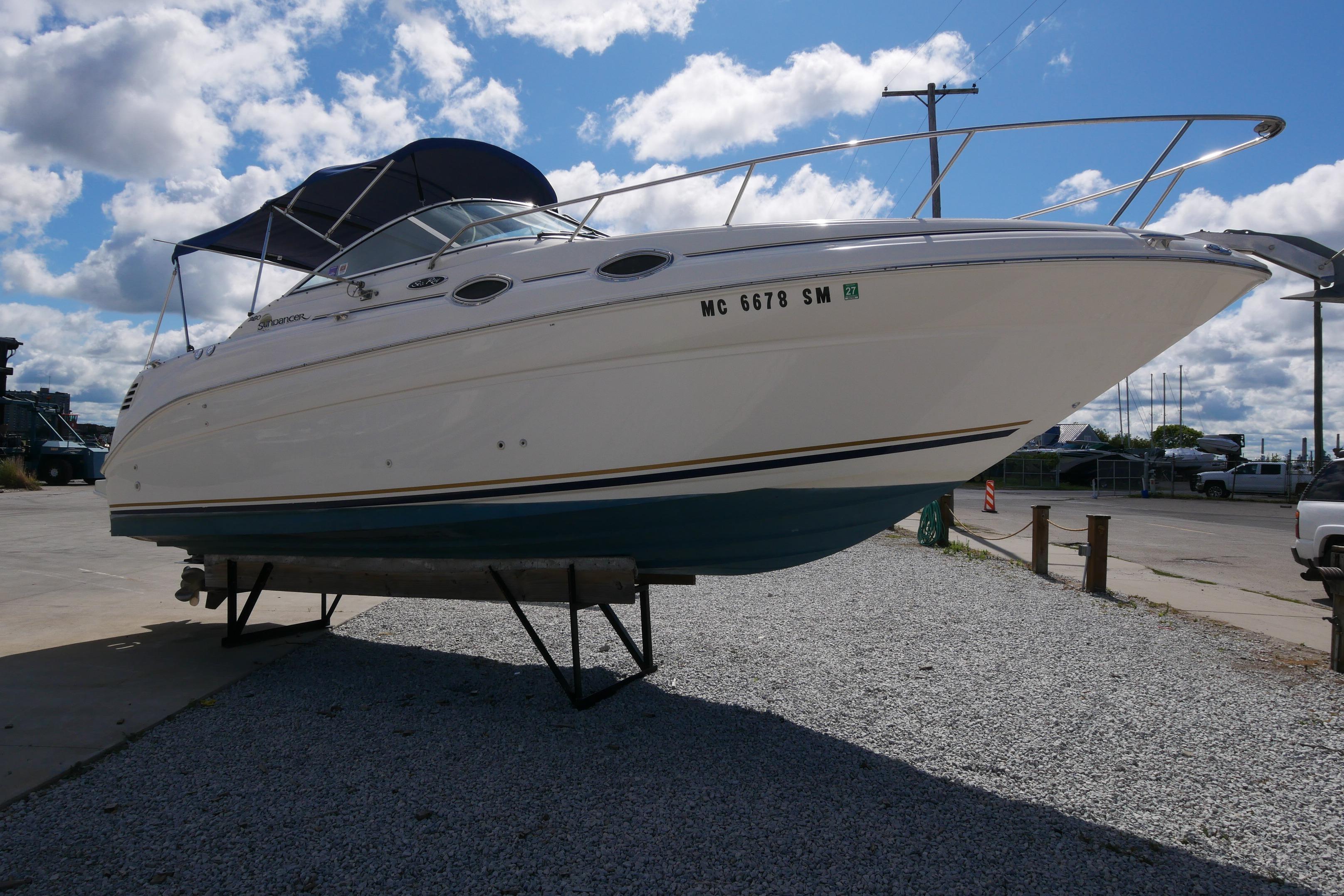 2003 Sea Ray 260 Sundancer boat on trailer under cloudy sky.