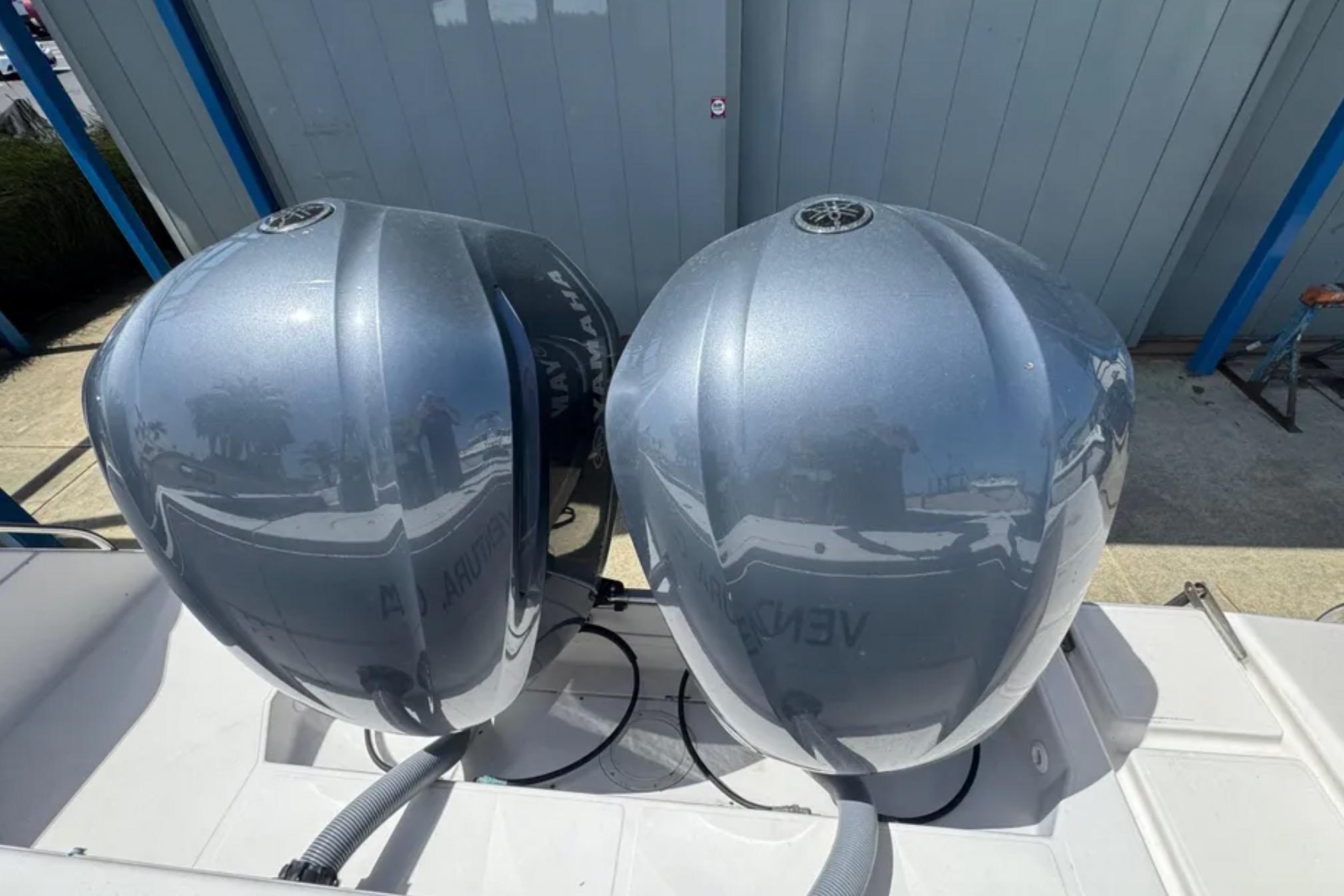 Twin outboard engines on a 1990 Grady-White Marlin 280 boat, reflecting surroundings.