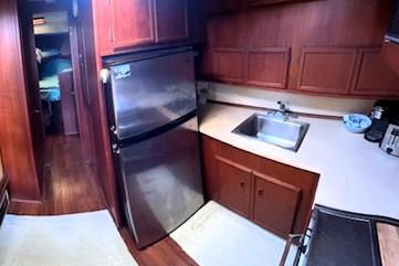 1980 Viking 43 Convertible yacht kitchen with stainless steel fridge and wooden cabinetry.