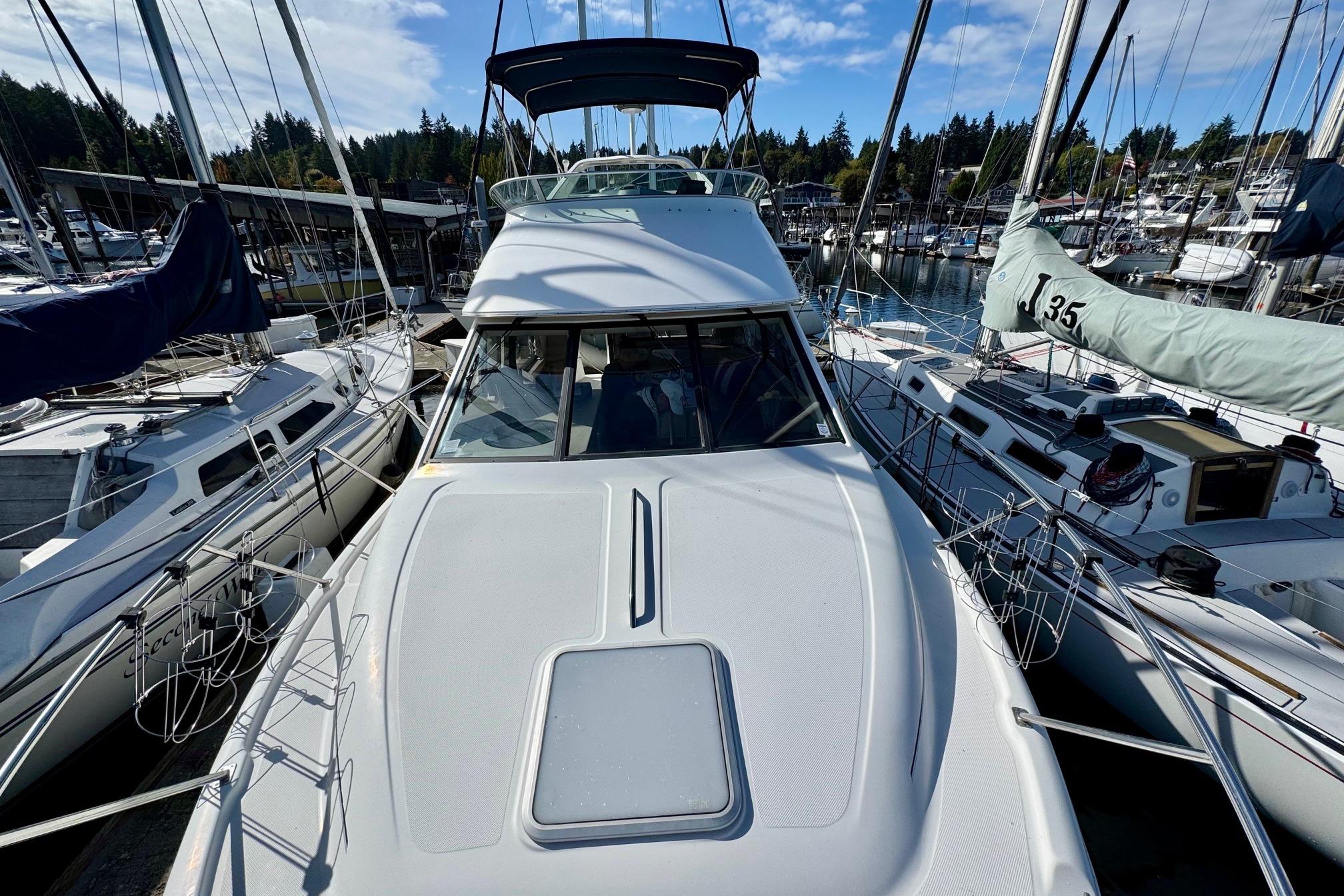 1998 Bayliner 3388 Command Bridge Motoryacht docked among sailboats in a marina.