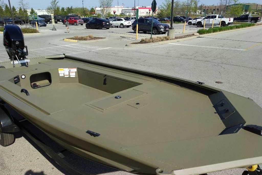2026 Tracker Grizzly 1654 T Sportsman boat in a parking lot, showcasing its spacious deck.