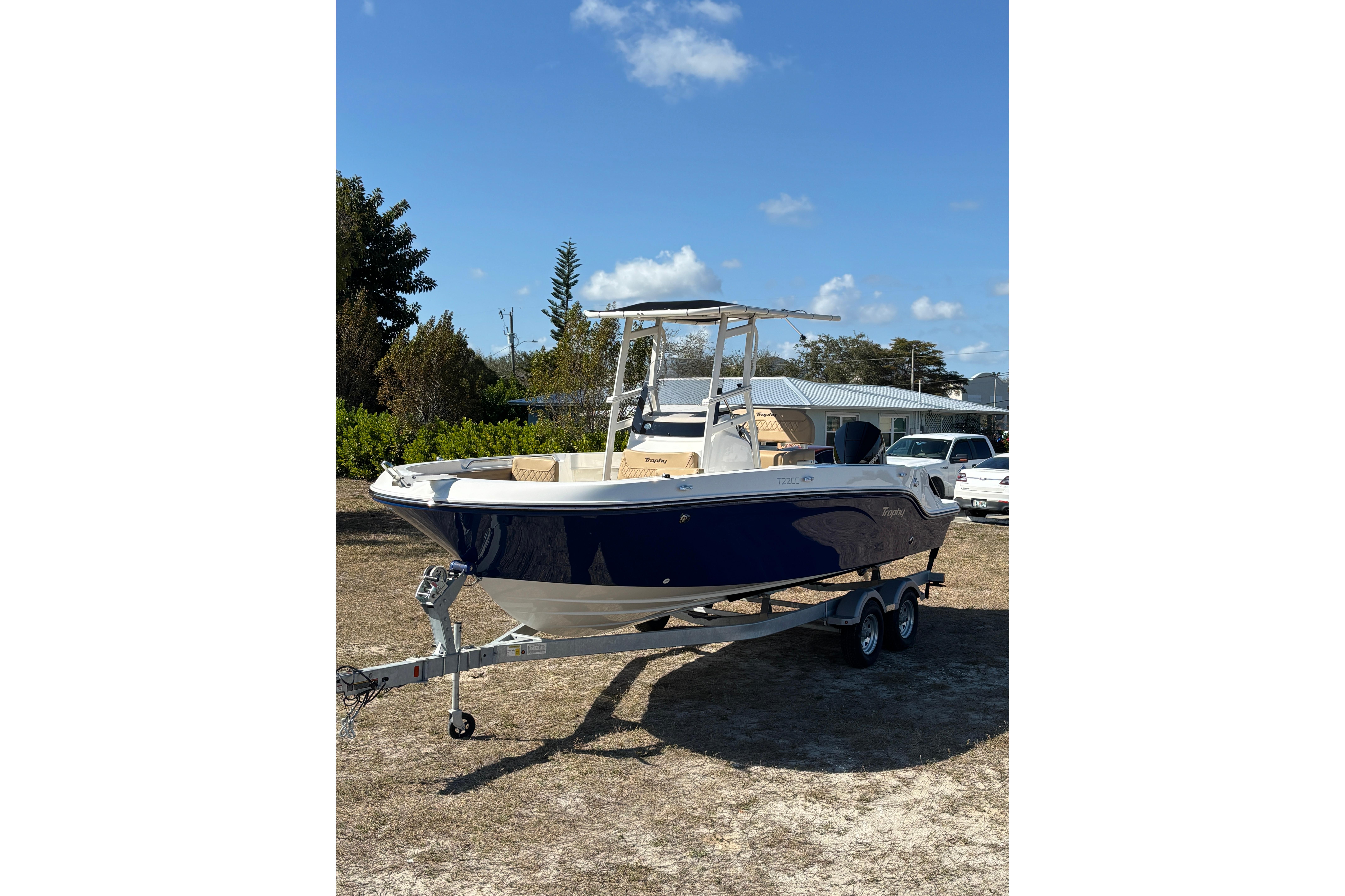 2026 Bayliner Trophy T22CC boat on trailer, parked outdoors under blue sky.